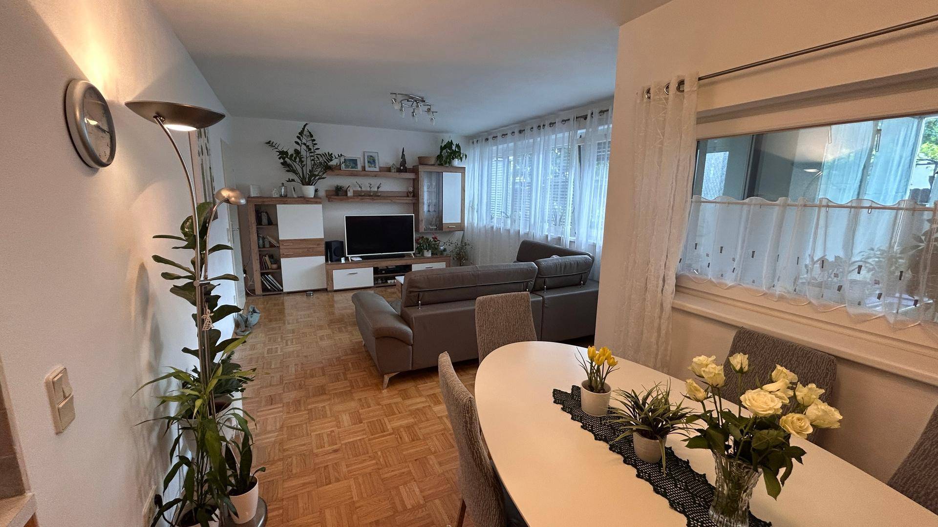 Gemütlicher Wohn-Essbereich mit Parkettboden, Sofa und Esstisch, hell durch große Fenster.