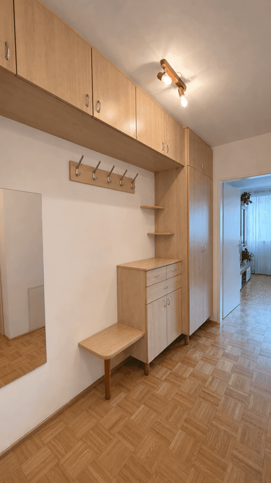 Heller Flur mit praktischen Einbauschränken und Garderobe, ausgestattet mit Parkettboden.