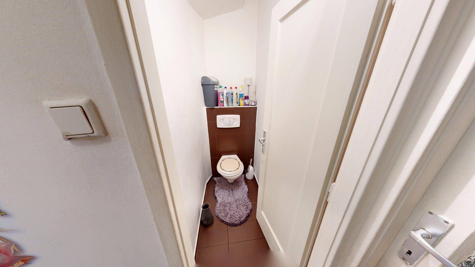 Kleines Gäste-WC mit wandhängender Toilette und Fliesenboden.
