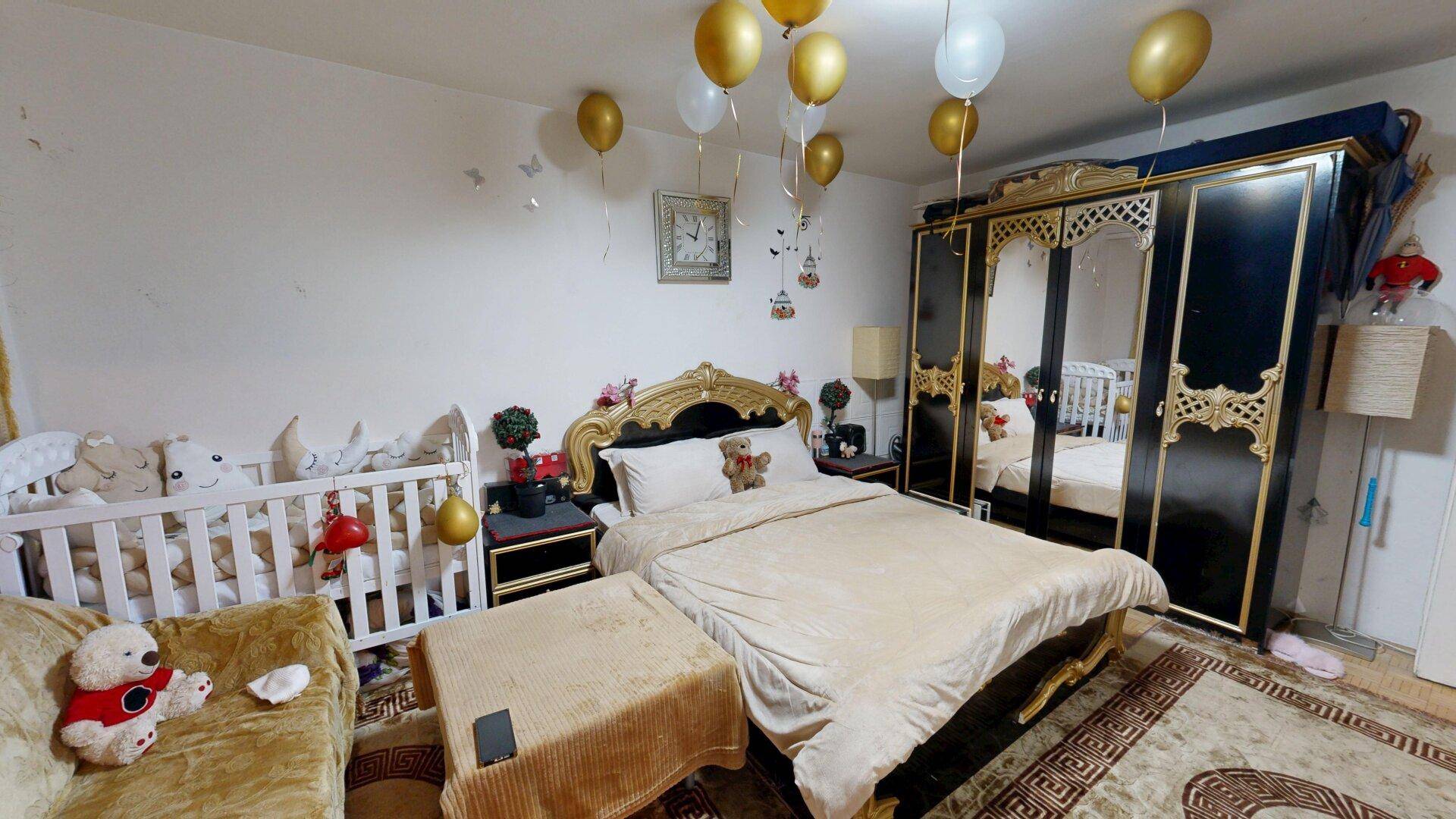 Schlafzimmer mit traditionellem Bett, Babybett und einem großen Kleiderschrank.