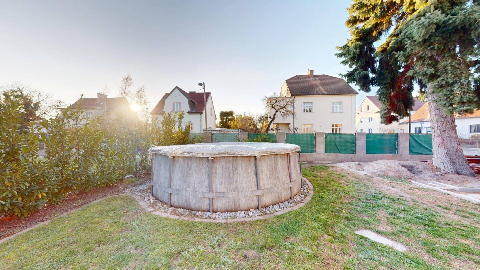 Großer Garten mit Rasenfläche und einem runden Aufstellpool für sommerliche Erfrischung.
