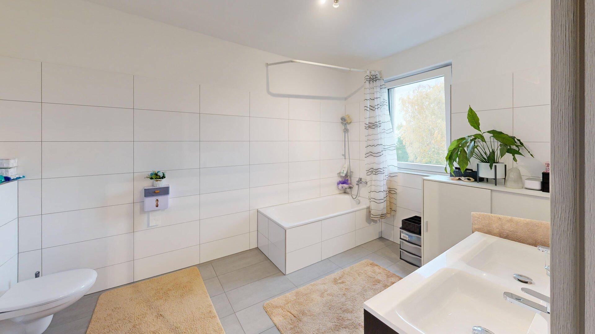 Geräumiges Badezimmer mit Badewanne, WC, Einzelwaschbecken und Fenster.