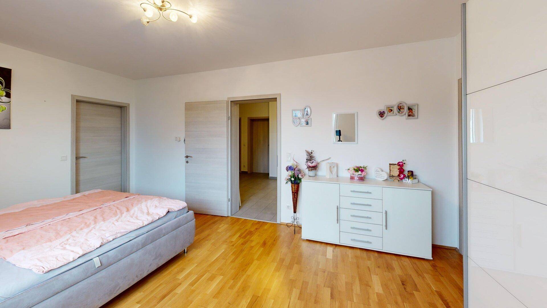 Geräumiges Schlafzimmer mit Parkettboden und Zugang zu weiteren Räumen.