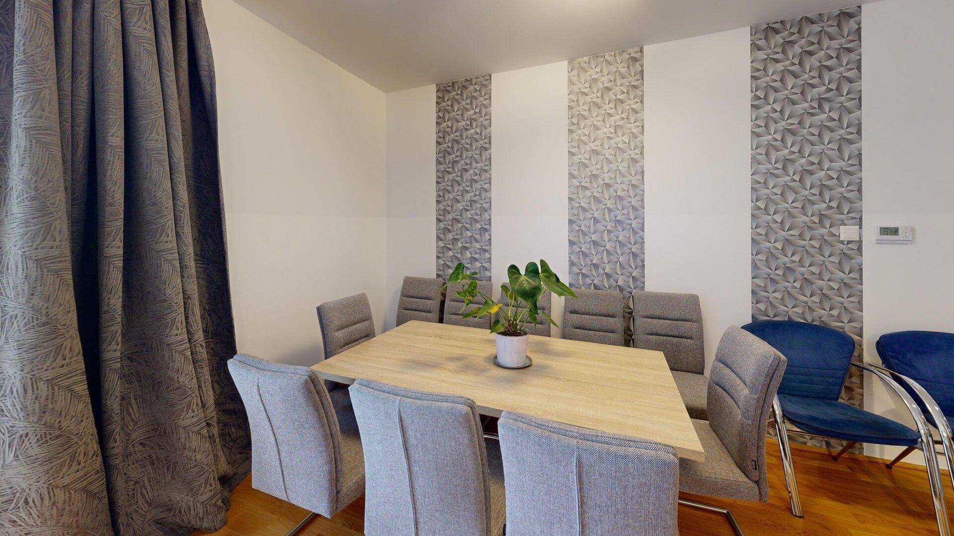 Essbereich mit großem Holztisch und bequemen Stühlen, ideal für Familienmahlzeiten.