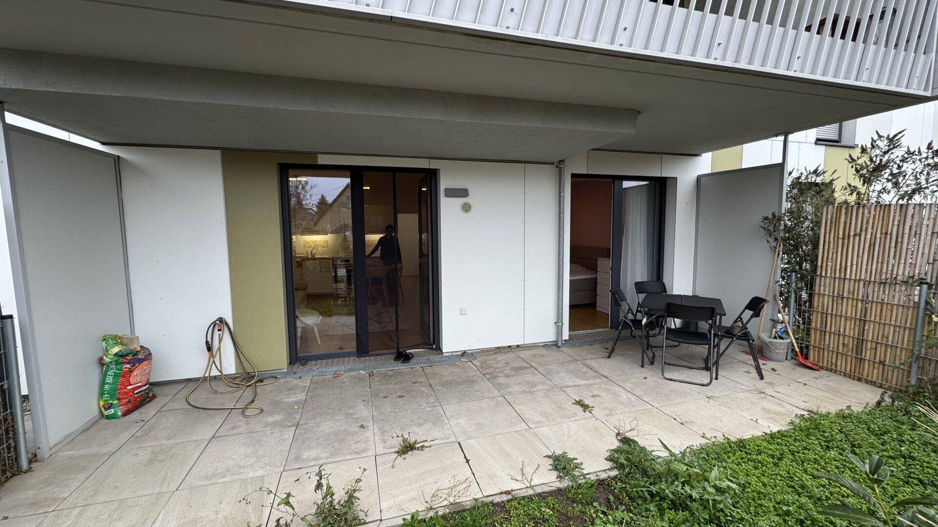Breite Terrasse mit Zugang von mehreren Räumen und Blick auf den Garten.