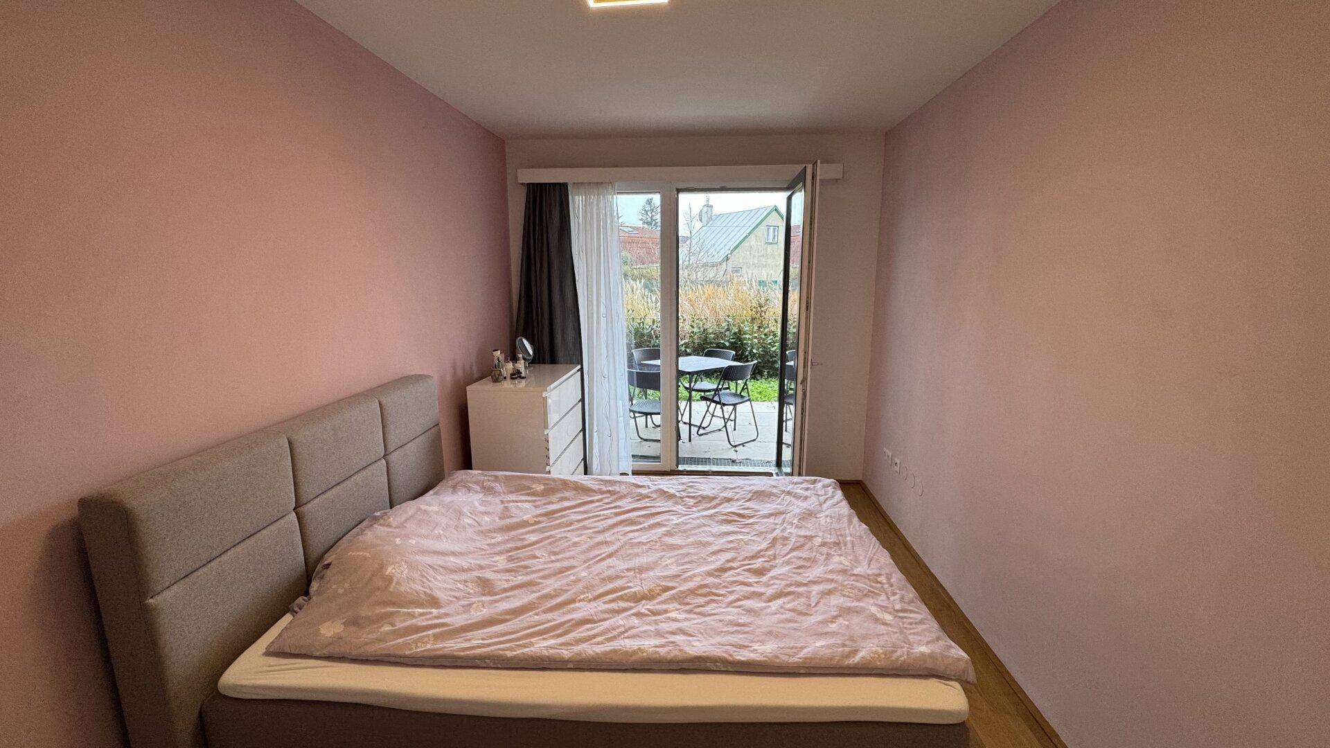 Helles Schlafzimmer mit Zugang zur Terrasse und Blick in den Garten.