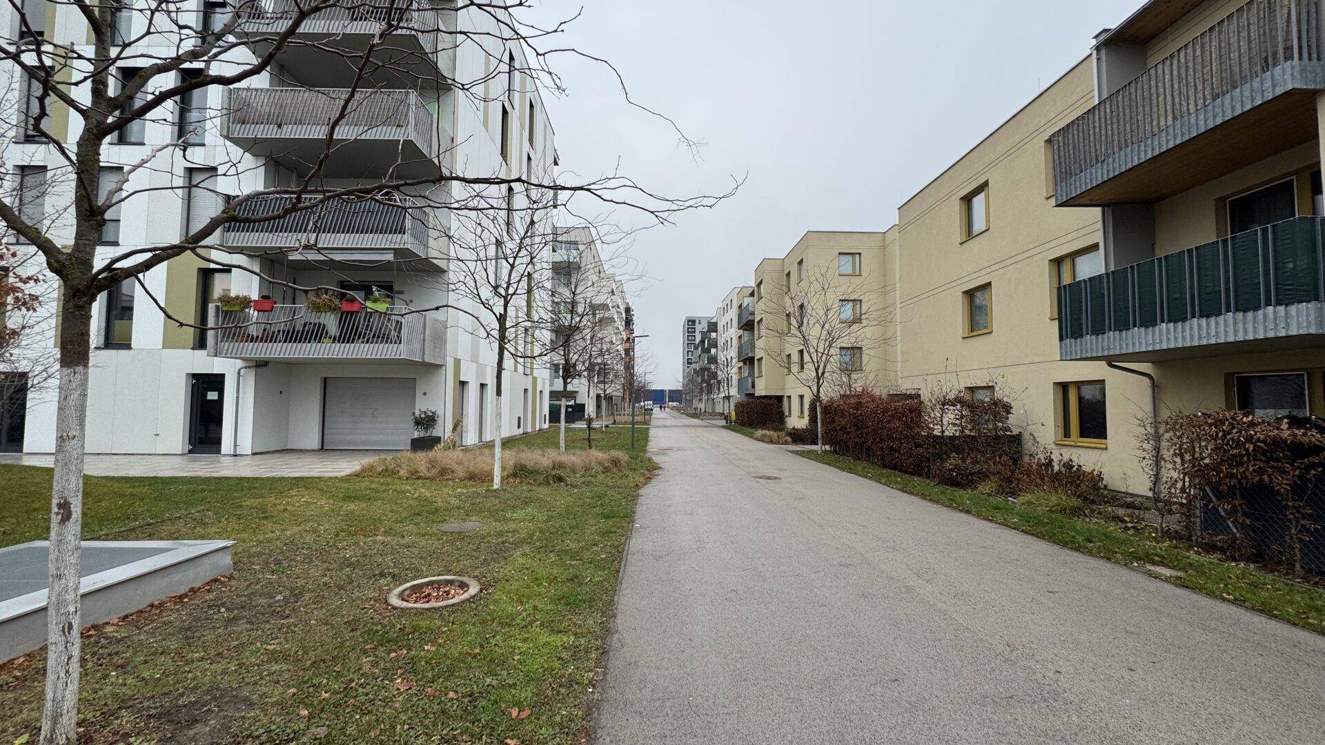 Wohnsiedlung mit modernen Mehrfamilienhäusern, Gehwegen und Bäumen.