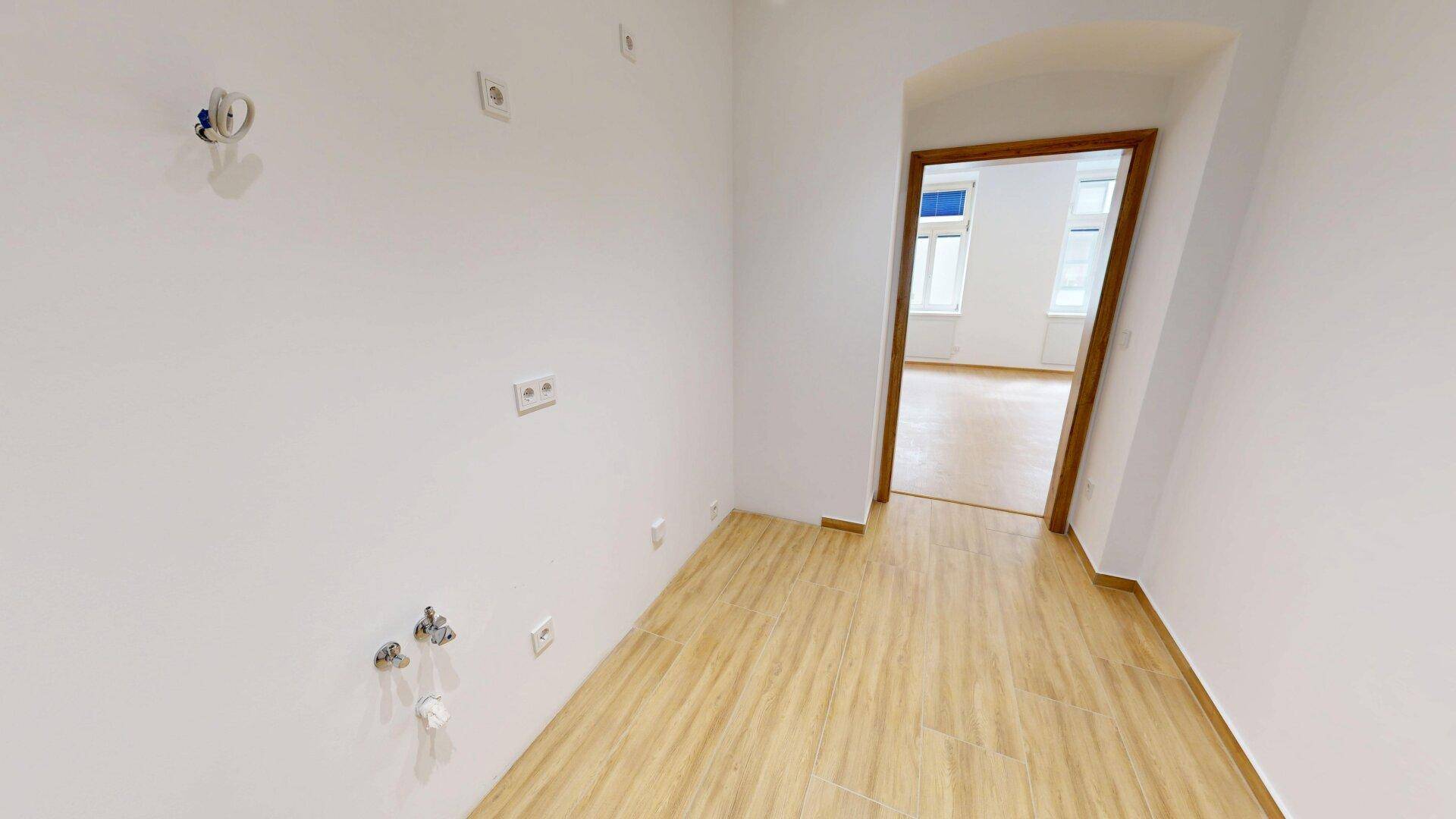 Raum mit Anschlüssen für Küche oder Waschmaschine und Zugang zu einem weiteren Zimmer.