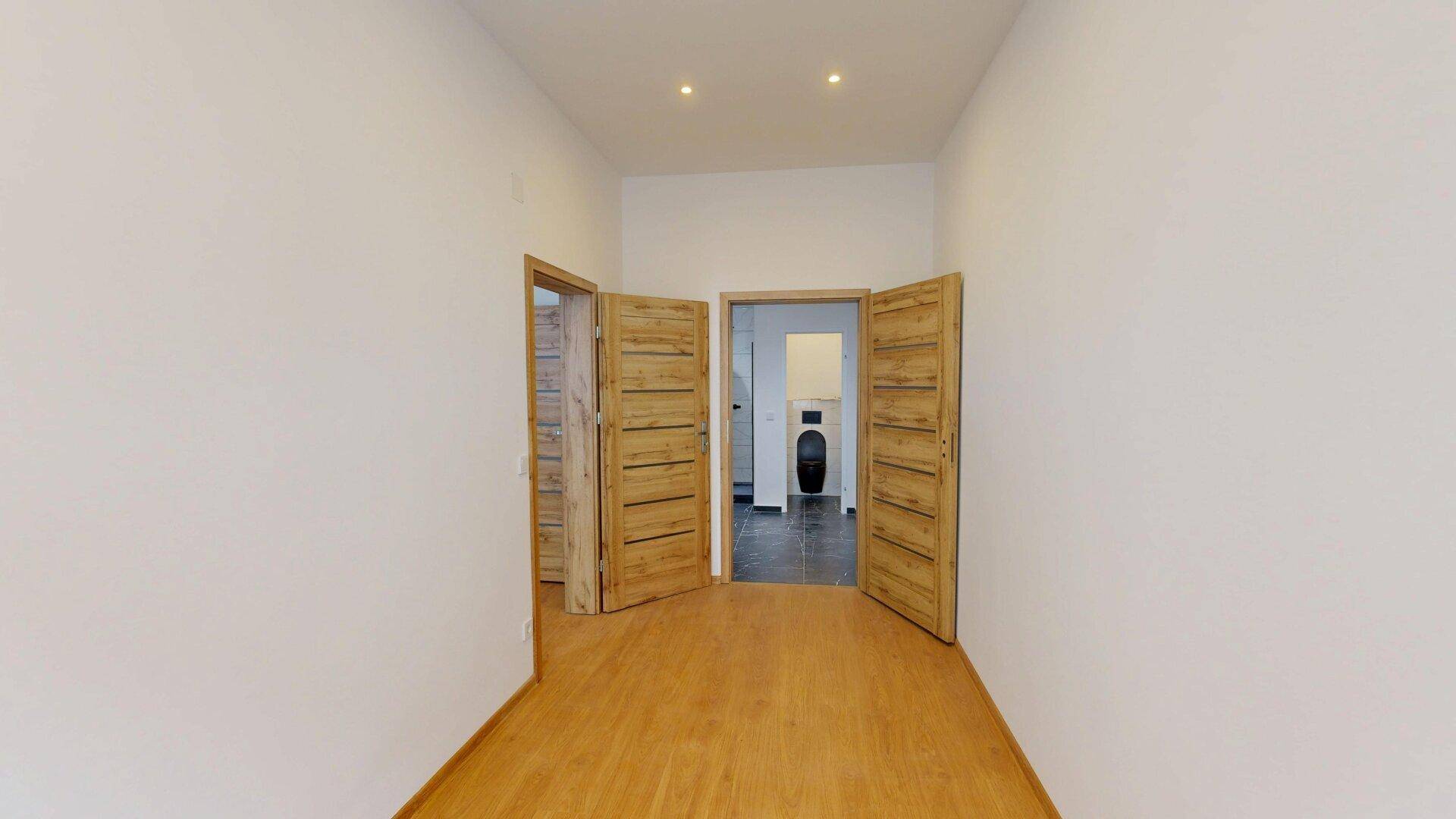 Heller Flur mit Holzfußboden und mehreren Holztüren, der zu weiteren Räumen führt.