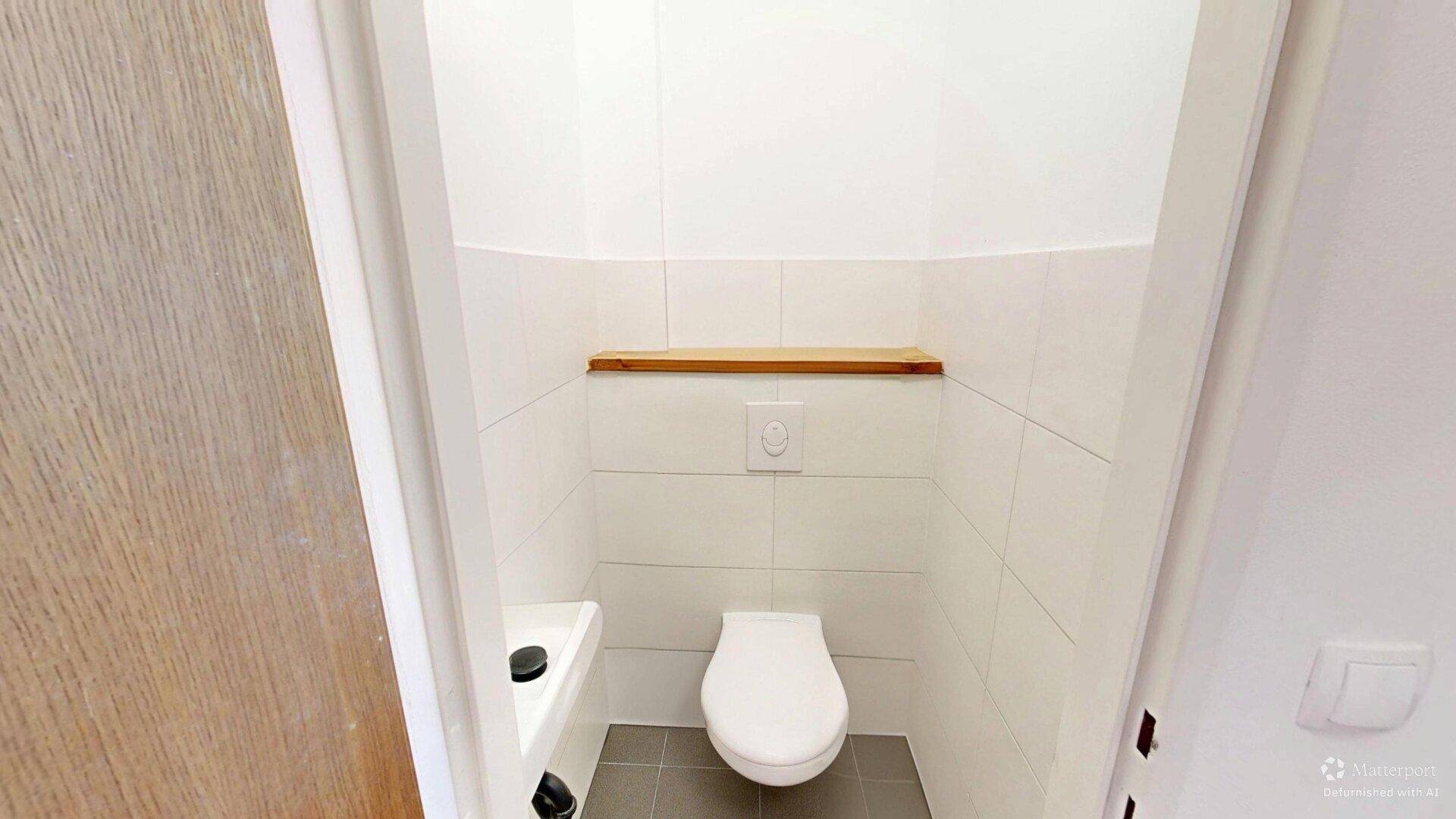 Separates Gäste-WC mit wandhängendem WC und kleinem Waschbecken.