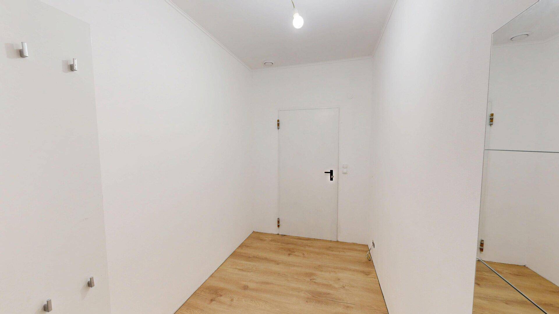 Heller Flur mit Laminatboden, Garderobe und großem Spiegel für den Eingangsbereich.