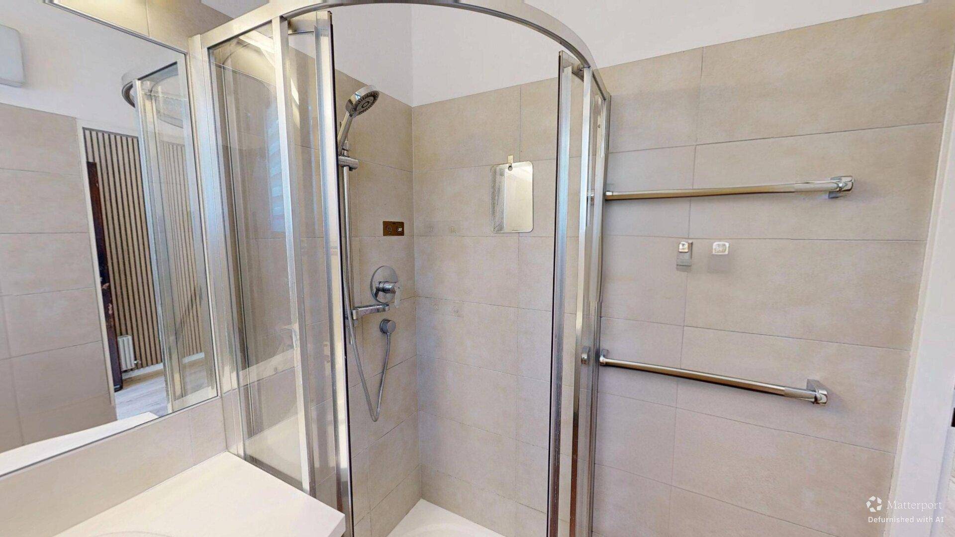 Modernes Badezimmer mit Duschkabine, beigefarbenen Fliesen und praktischem Handtuchhalter.