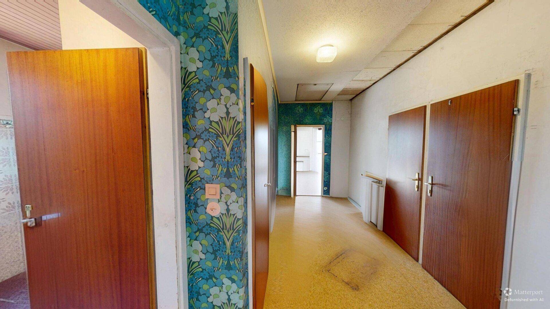 Flur mit auffälliger floraler Tapete, Holztüren und Teppichboden.