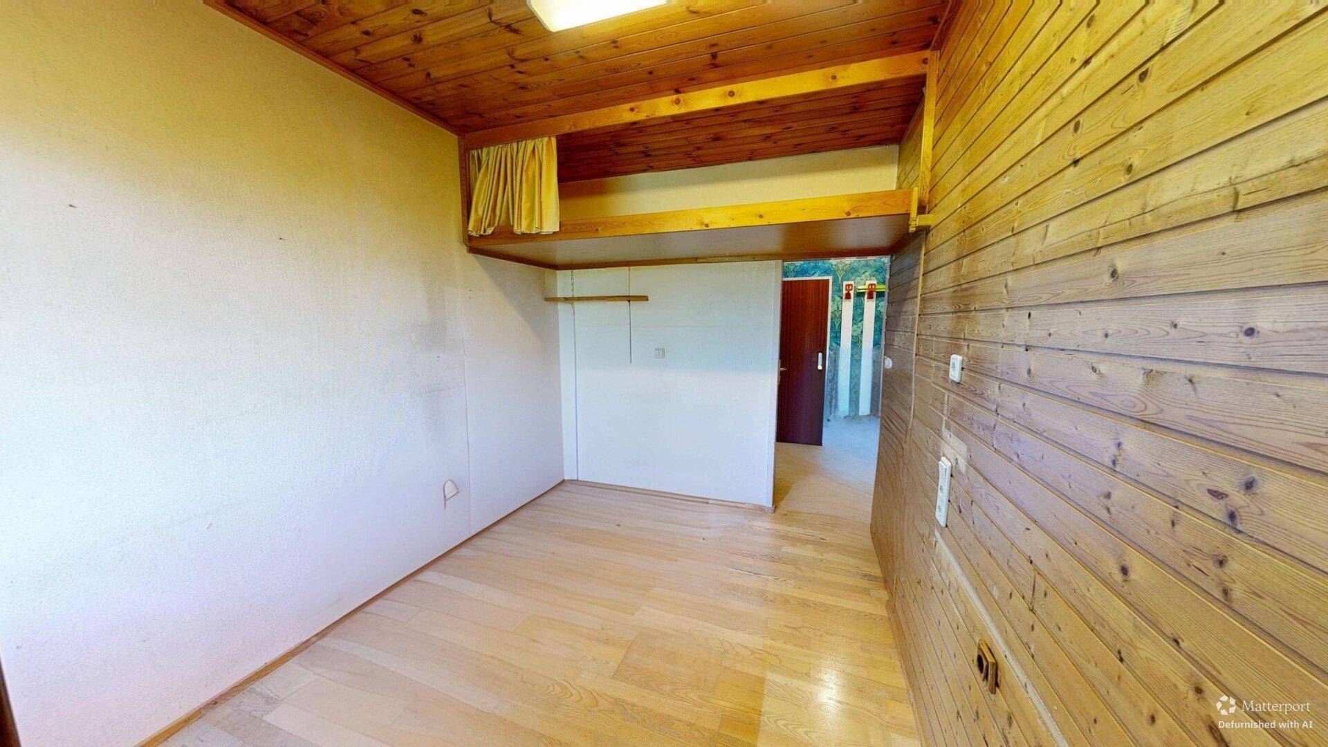 Schlafzimmer mit Holzvertäfelung, Holzdecke und hellem Laminatboden.