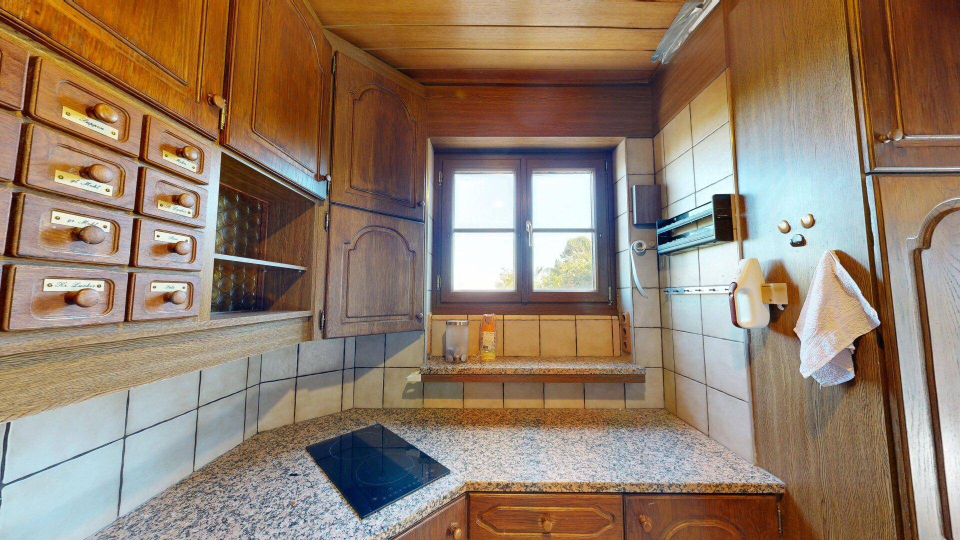 Traditionelle Küche mit Holzschränken, Granitarbeitsplatte und Induktionskochfeld.