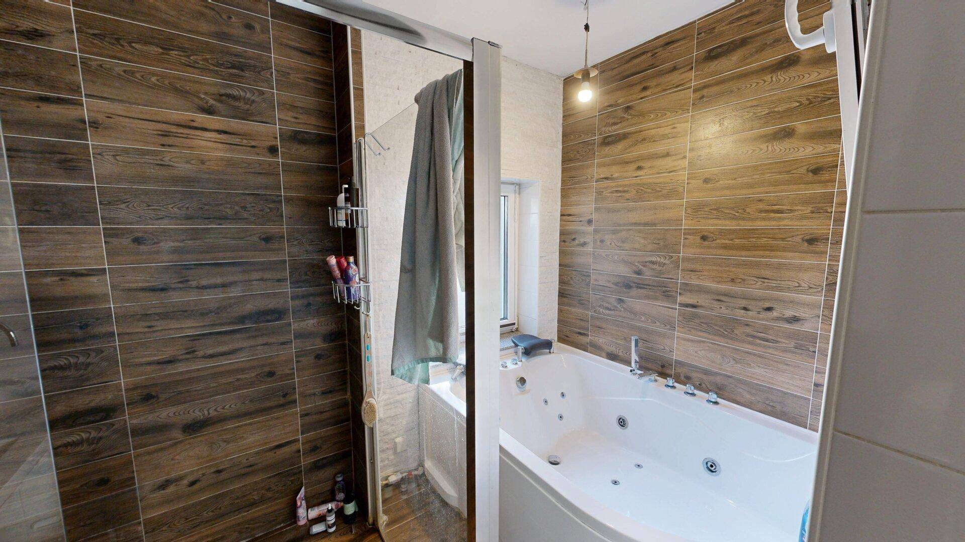 Badezimmer mit moderner Duschkabine und Eckbadewanne mit Whirlpool-Funktion.