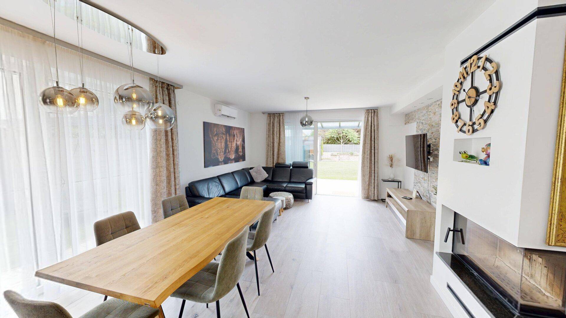 Geräumiger Wohn- und Essbereich mit Ledersofa, Holztisch und Zugang zum Garten.
