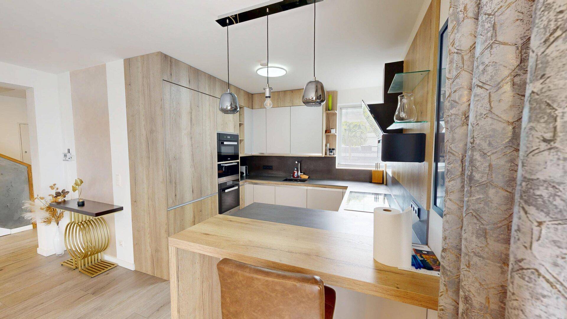 Moderne Küche mit Holzakzenten, integrierten Geräten und einer praktischen Frühstücksbar.