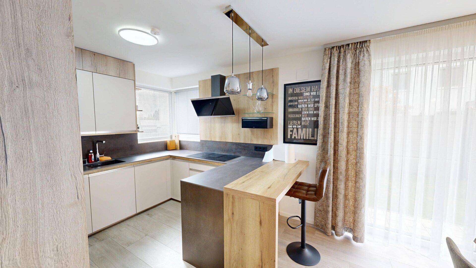 Helle, moderne Küche mit Kochinsel, integrierten Geräten und Zugang zur Terrasse.