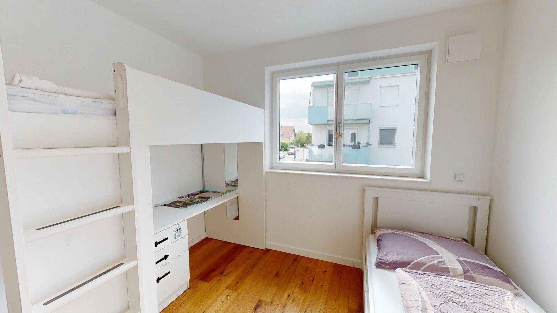 Kinderzimmer mit Hochbett, Schreibtisch und Holzboden, hell und funktional eingerichtet.