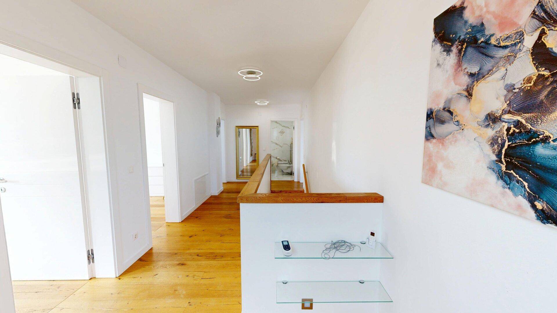 Heller Flur im Obergeschoss mit Holzfußboden und moderner Kunst an der Wand.