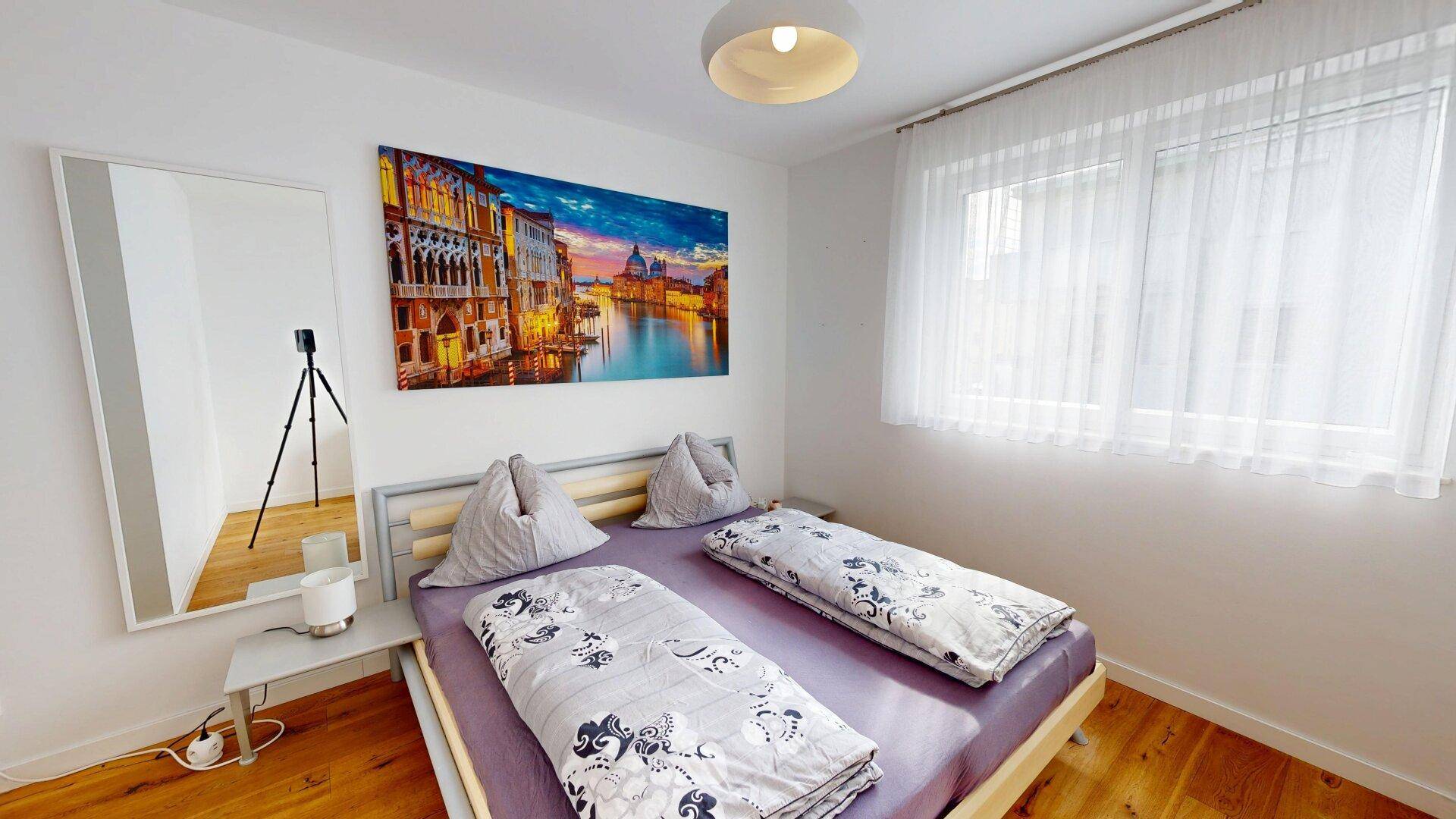 Gemütliches Schlafzimmer mit Doppelbett, Holzboden und großem Wandbild.