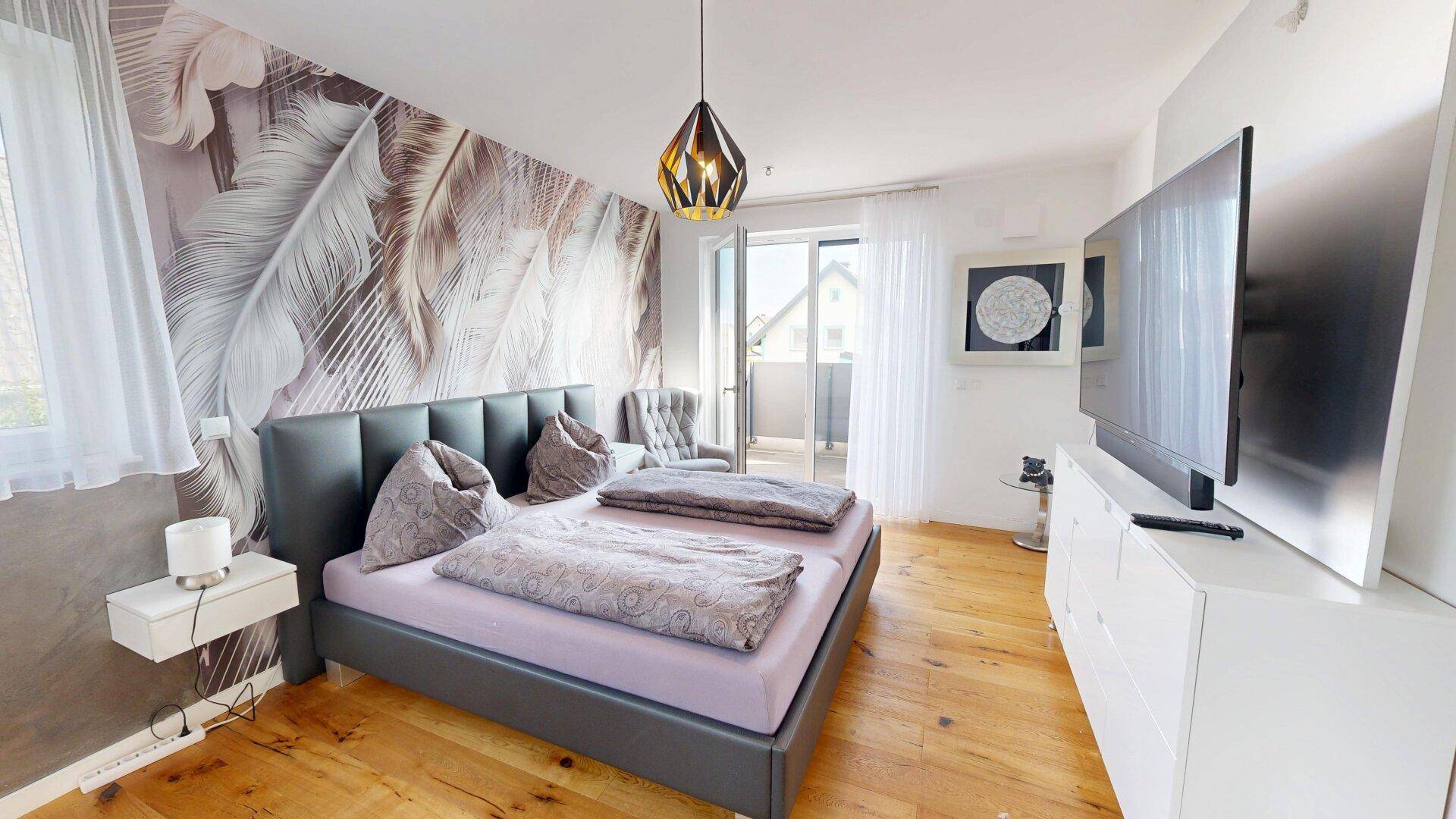 Geräumiges Schlafzimmer mit Balkonzugang, Holzboden und moderner Wandgestaltung.