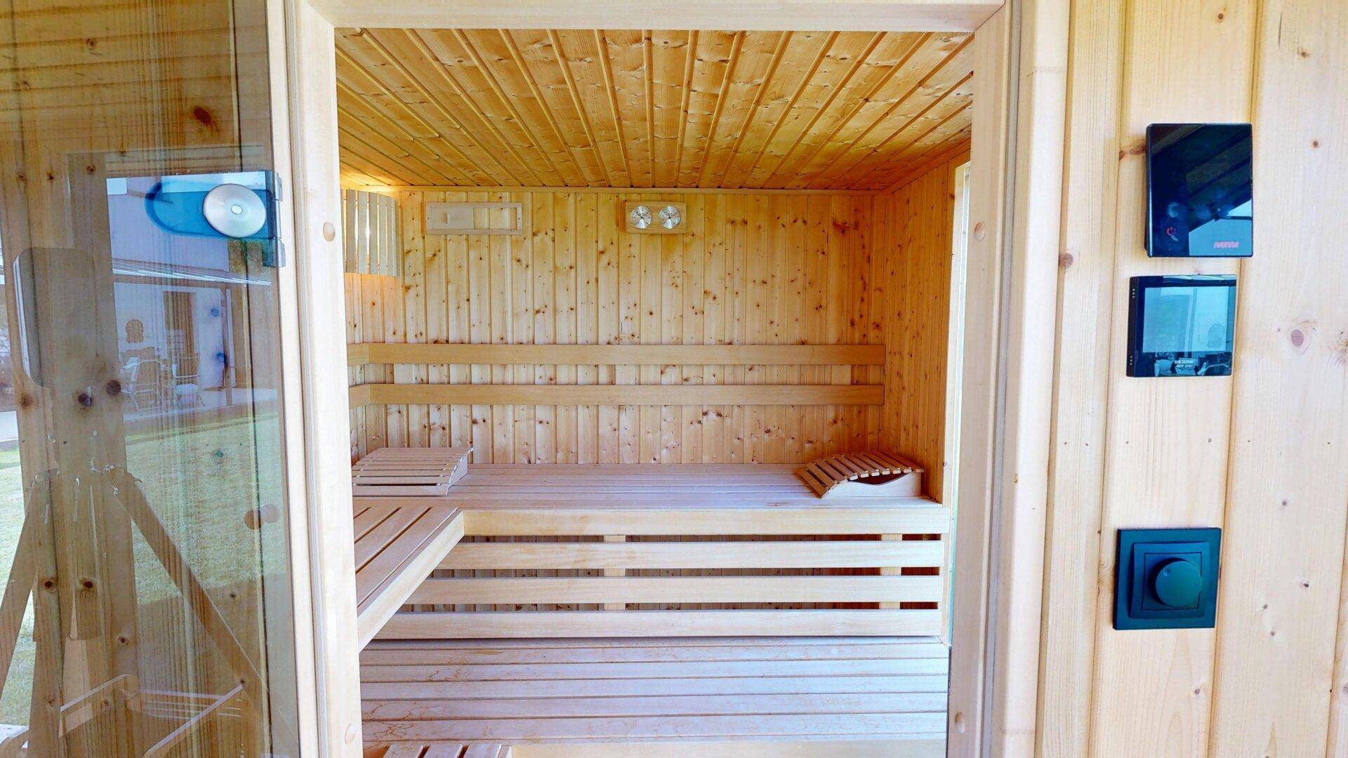 Moderne Holzsauna mit mehreren Bänken und Steuerungselementen für Entspannung.