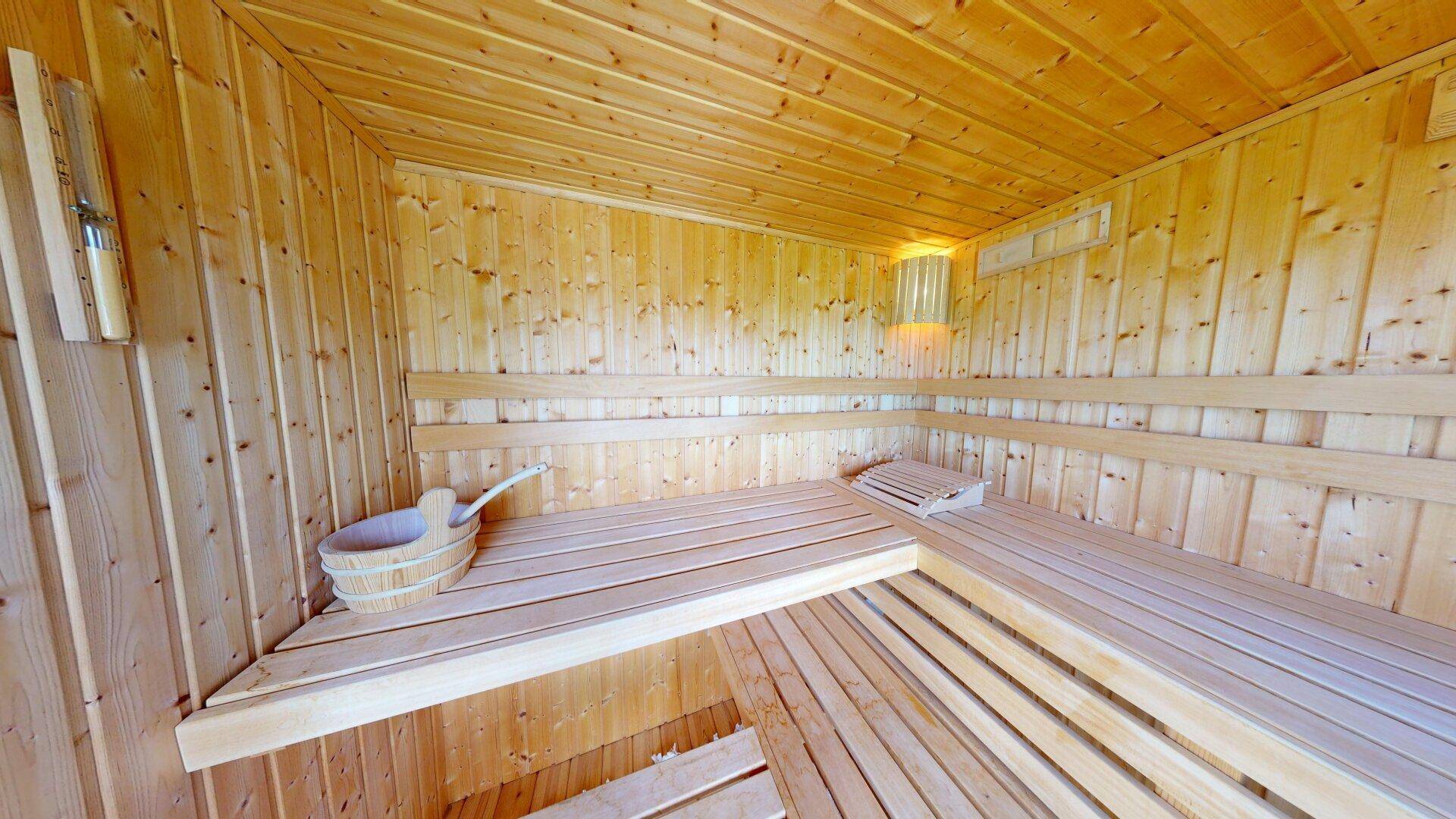 Geräumige Holzsauna mit traditionellem Eimer und Schöpfkelle für Aufgüsse.