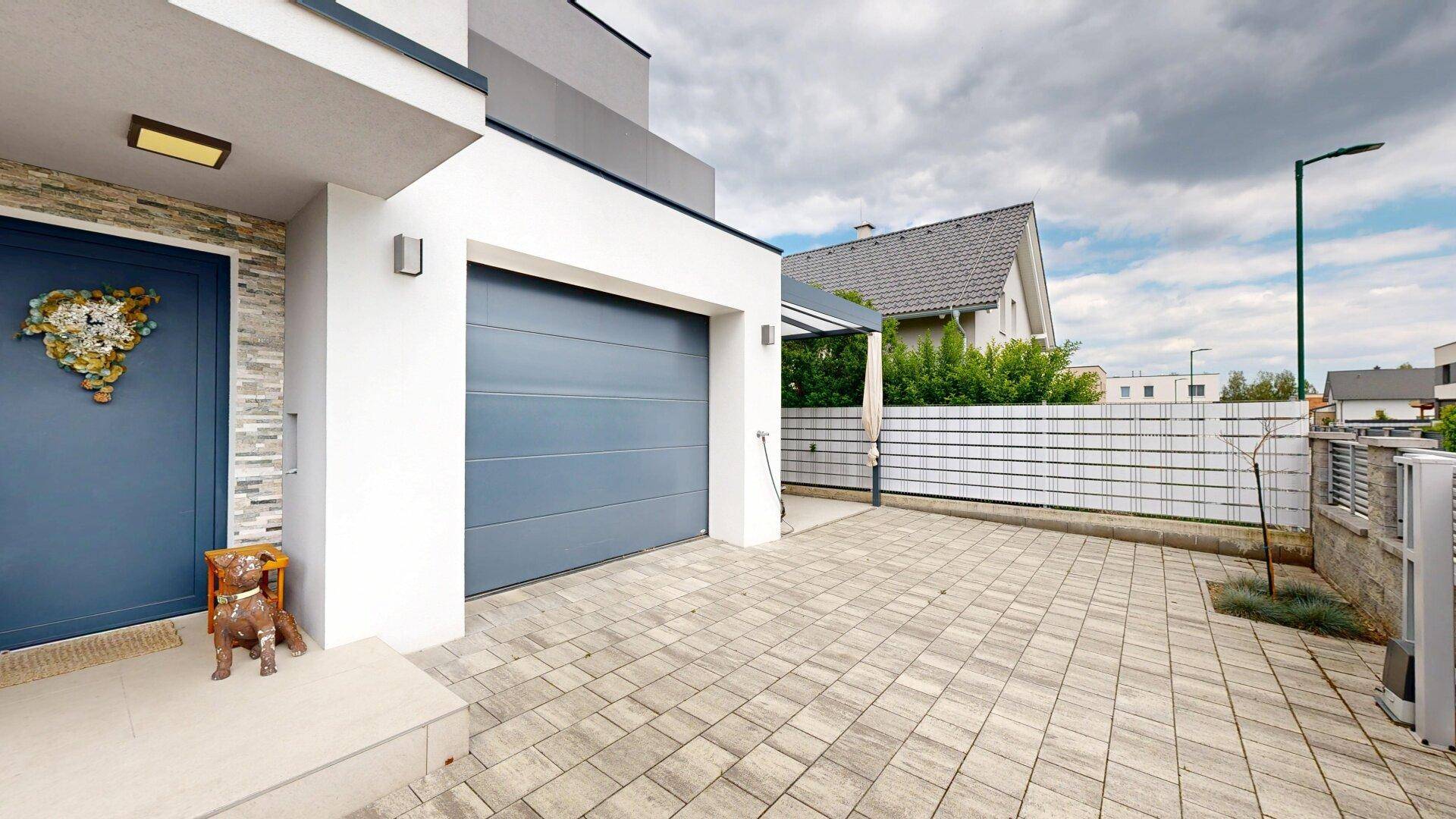 Hauseingang mit Garage und gepflasterter Auffahrt, modern und einladend gestaltet.