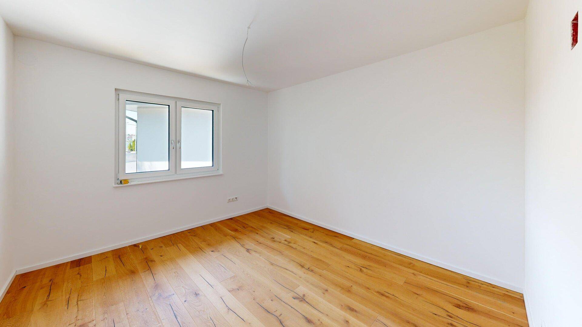 Ruhiges Schlafzimmer mit Holzboden und großem Fenster für viel Tageslicht.