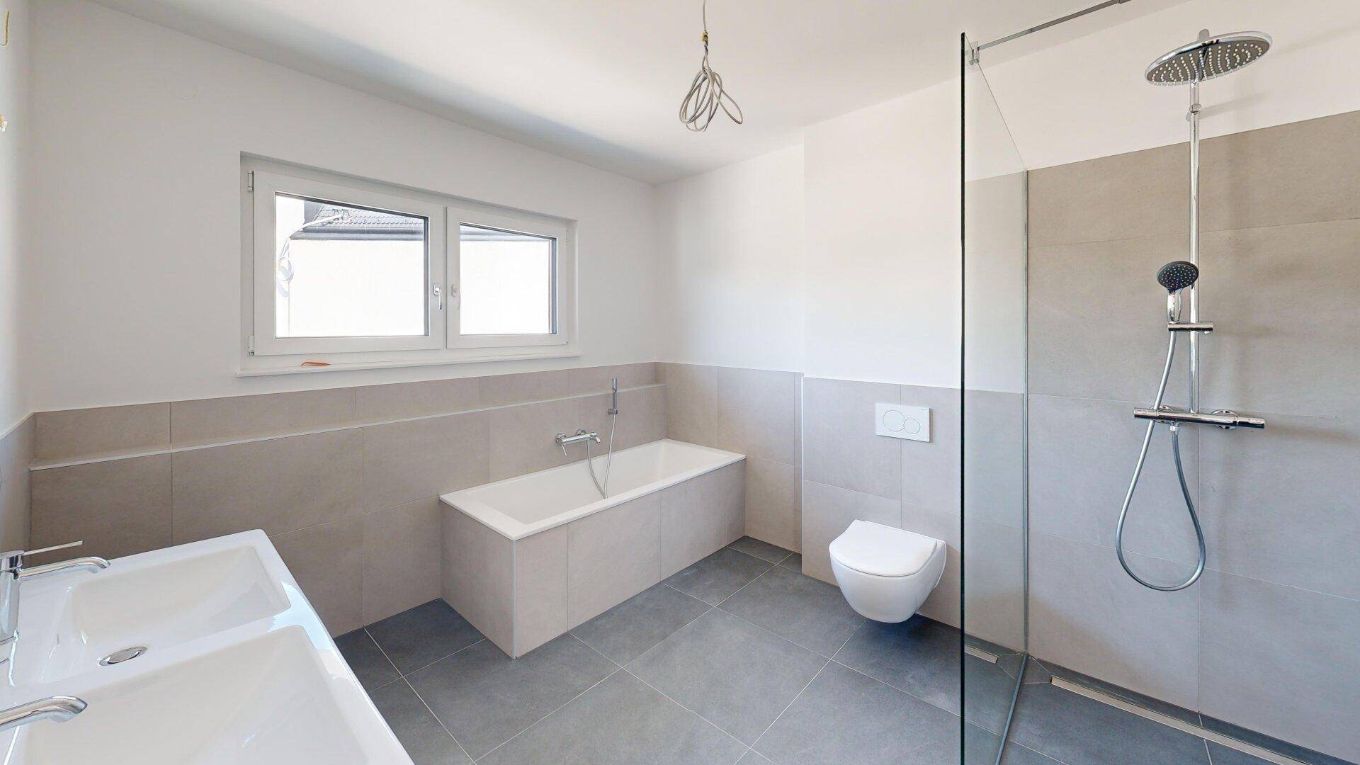 Modernes Badezimmer mit Doppelwaschbecken, Badewanne, bodengleicher Dusche und Fenster.