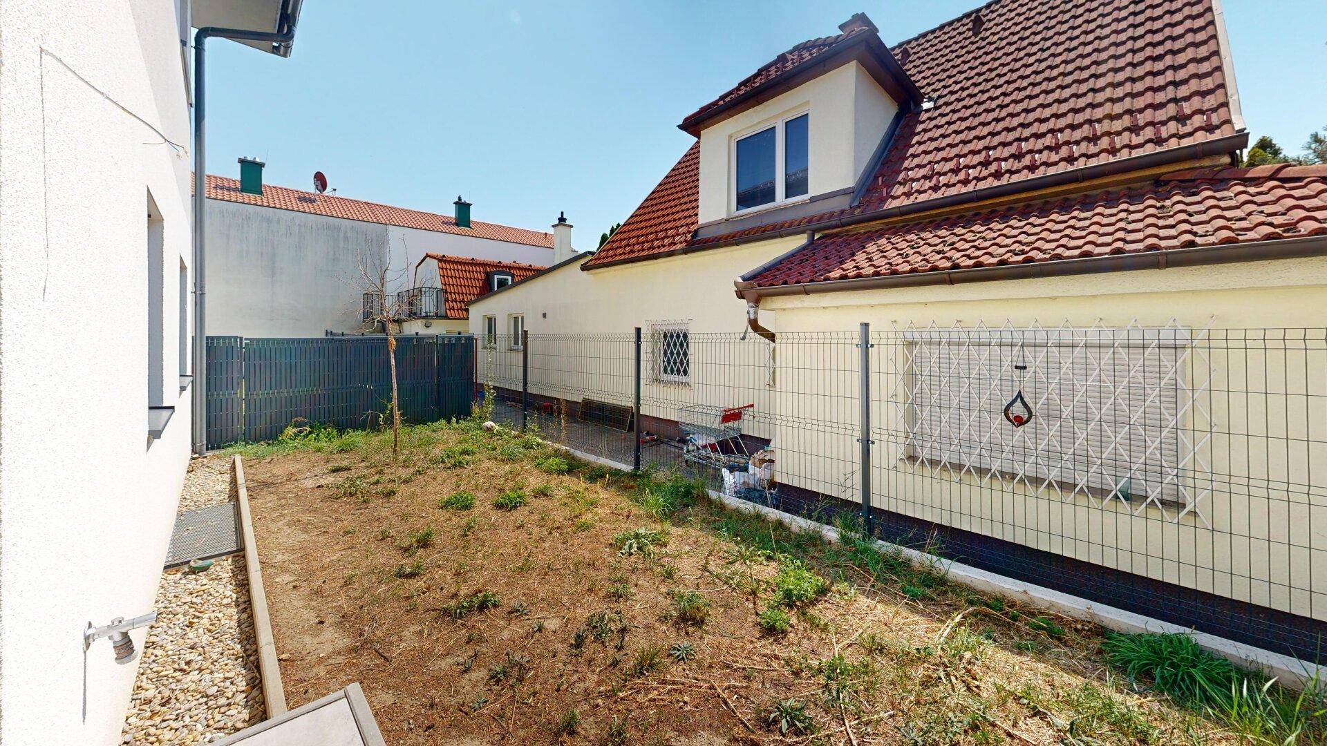 Seitenansicht des Hauses mit Gartenfläche und angrenzendem Nachbargebäude.