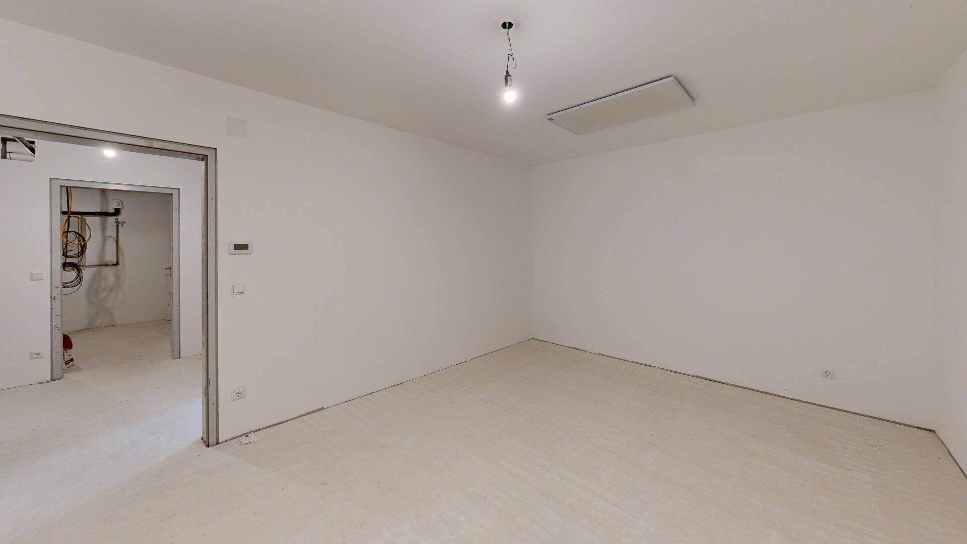 Unfertiger Hauswirtschaftsraum mit Betonboden und sichtbaren Installationen.