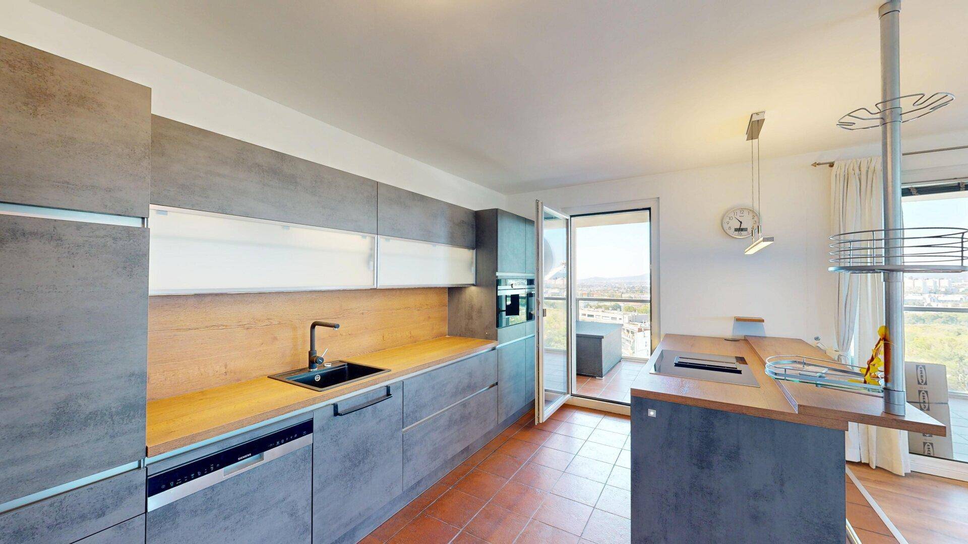 Gut ausgestattete moderne Küche mit integriertem Geschirrspüler und Zugang zum Balkon.