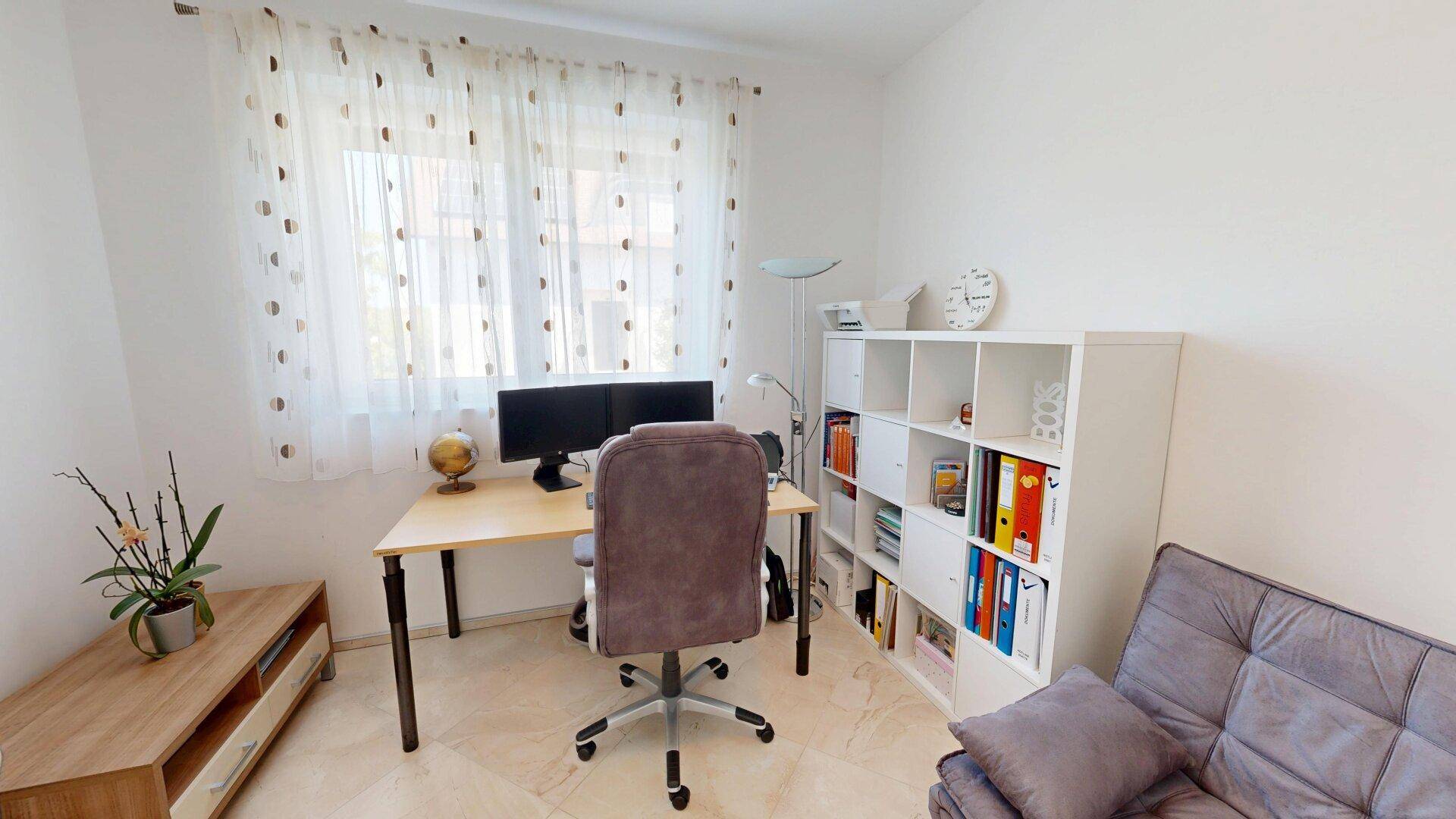 Helles Arbeitszimmer mit Schreibtisch, Bürostuhl und Regalen am Fenster für produktives Arbeiten.