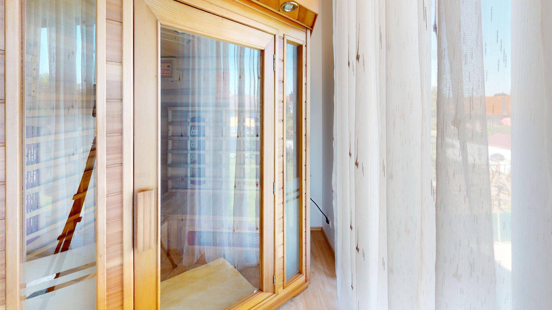 Holzvertäfelte Sauna mit Glastür und Blick nach draußen, ideal zur Entspannung.