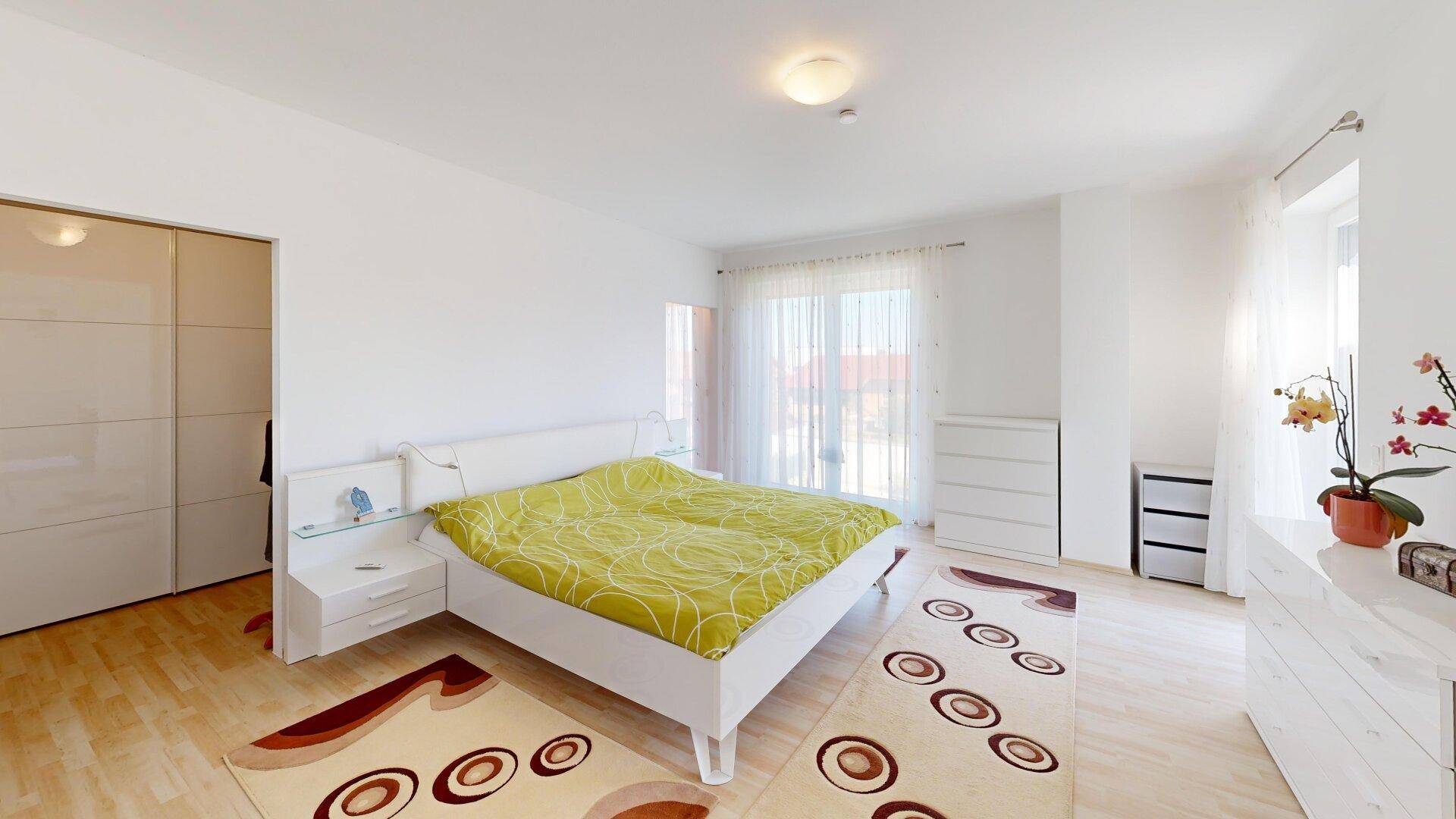 Helles Schlafzimmer mit Doppelbett, Einbauschränken und hellem Holzboden für eine gemütliche Atmosphäre.