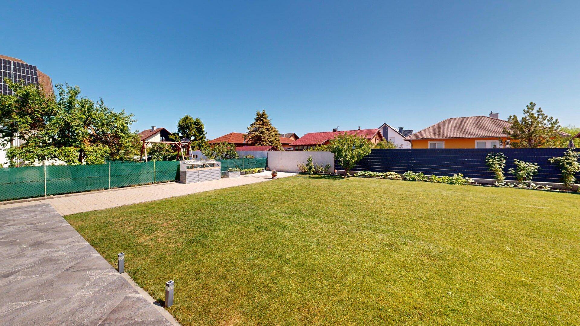 Großer, gepflegter Garten mit weitläufiger Rasenfläche und umliegenden Häusern in ruhiger Lage.