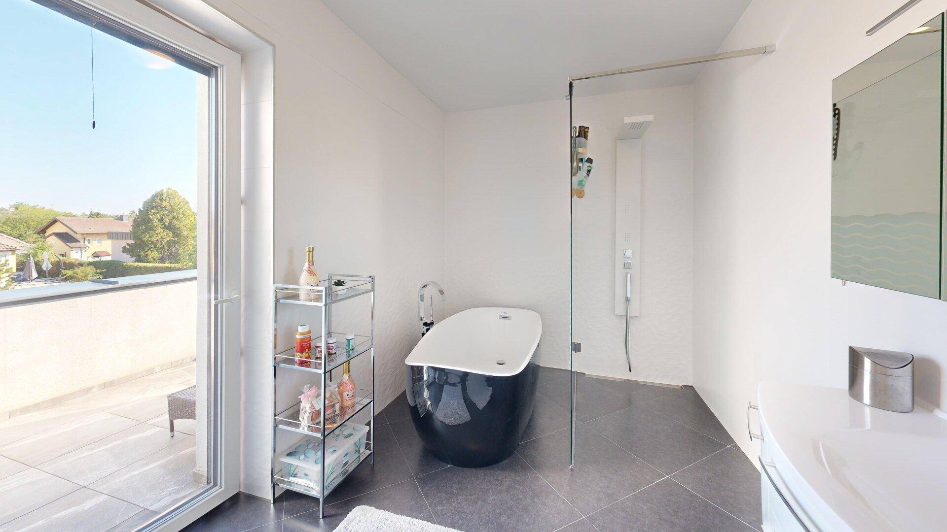 Modernes Badezimmer mit freistehender Badewanne, Dusche und Zugang zur sonnigen Terrasse.
