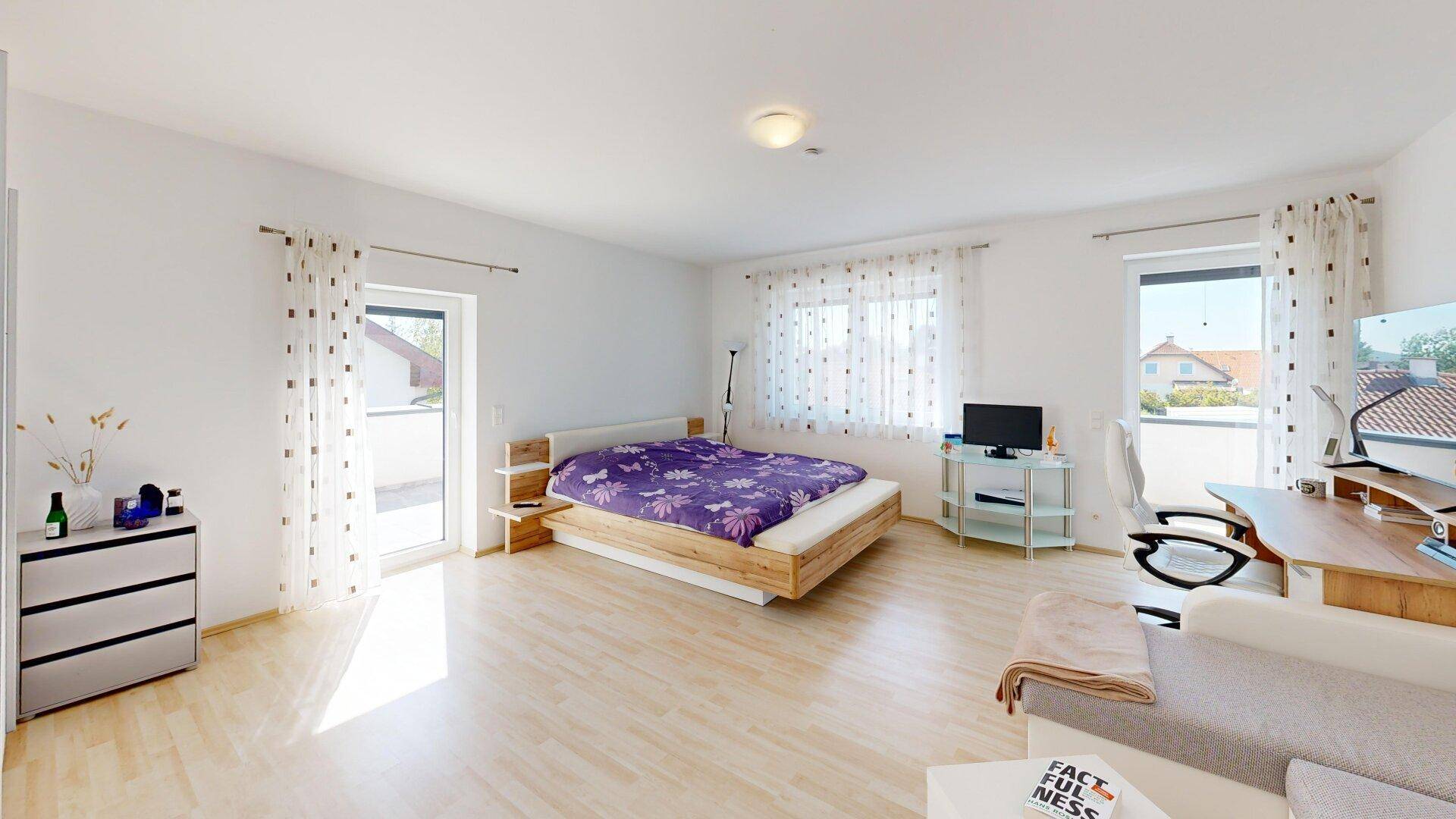 Helles Schlafzimmer mit Doppelbett, Schreibtisch und Zugang zum Balkon für frische Luft.