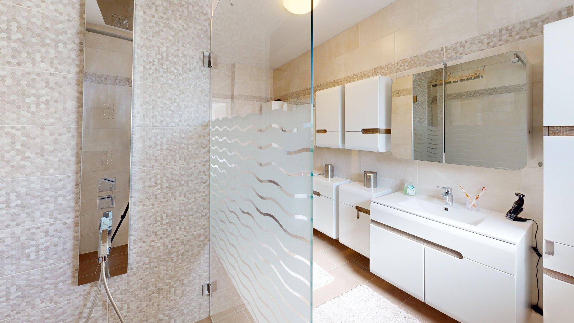 Modernes Badezimmer mit Duschkabine, Einzelwaschbecken und hellen Fliesen für ein frisches Ambiente.