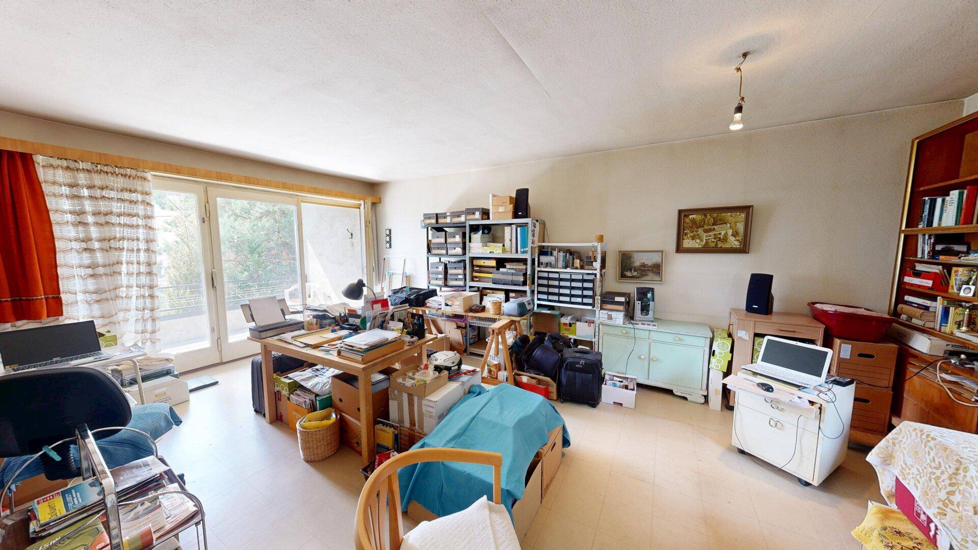 Geräumiger Wohnraum mit Schreibtisch, Regalen und Zugang zu einem sonnigen Balkon, vielseitig nutzbar.