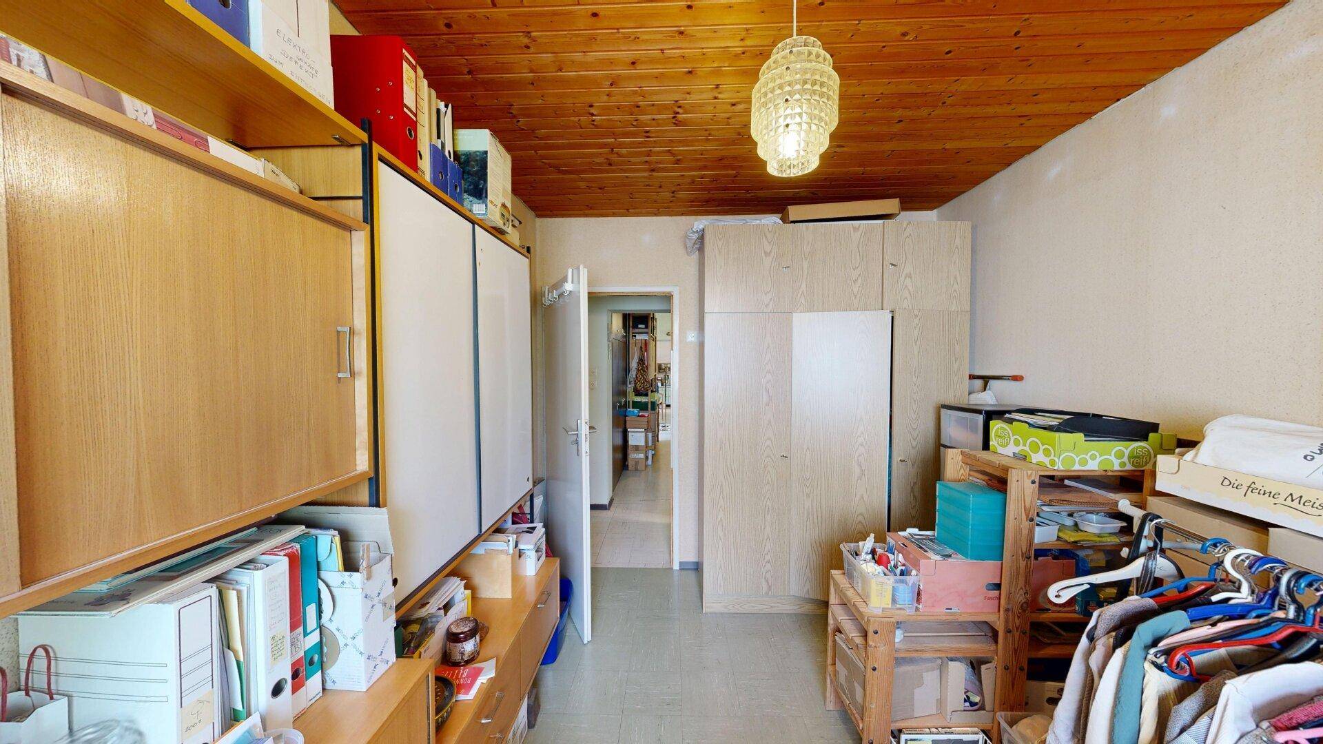 Praktischer Abstellraum mit Holzdecke, vielen Regalen und Schränken für diverse Gegenstände und Lagerung.