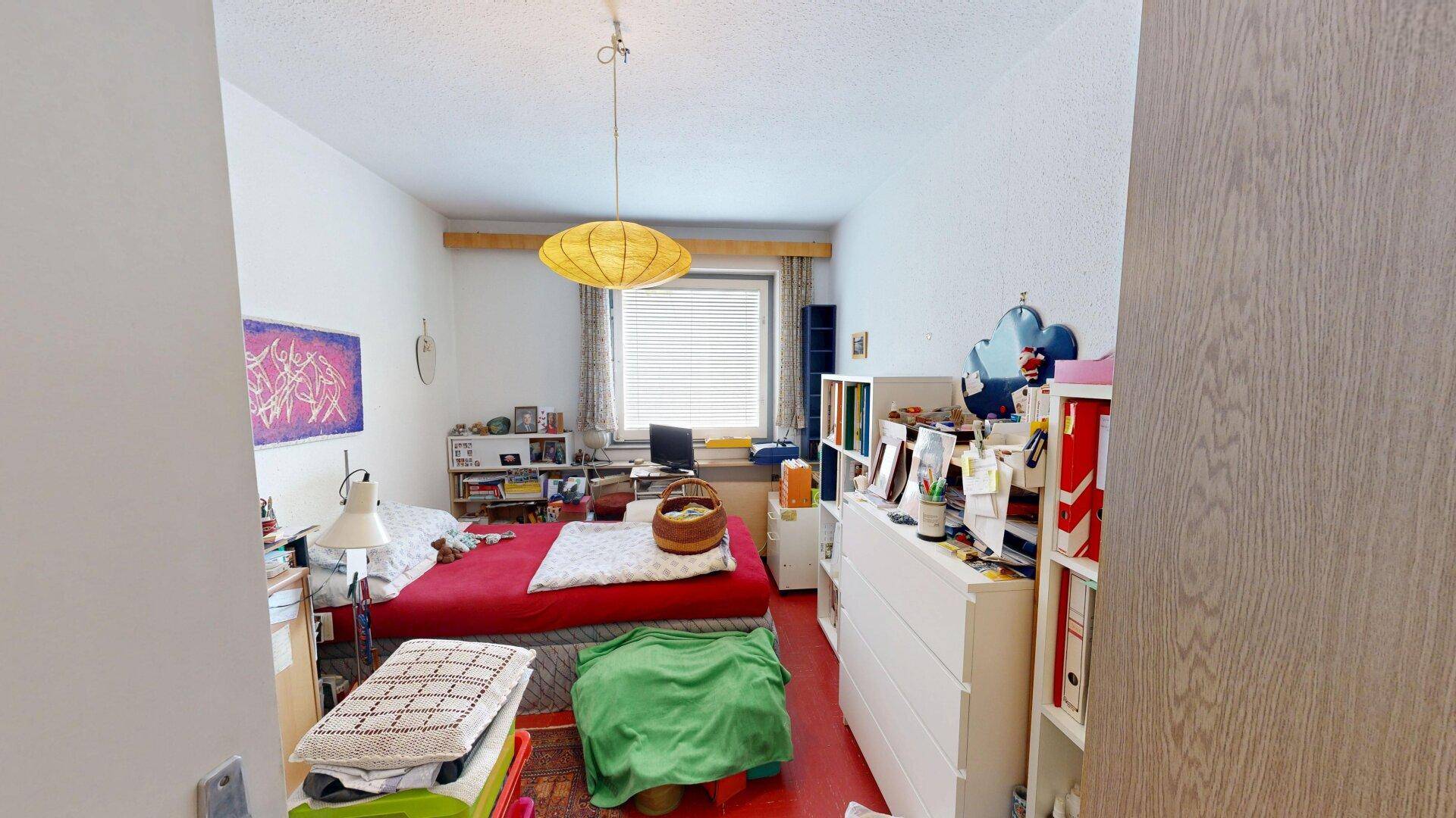 Gemütliches Schlafzimmer mit Einzelbett, Kommode und Fenster mit Jalousien, hell und funktional eingerichtet.
