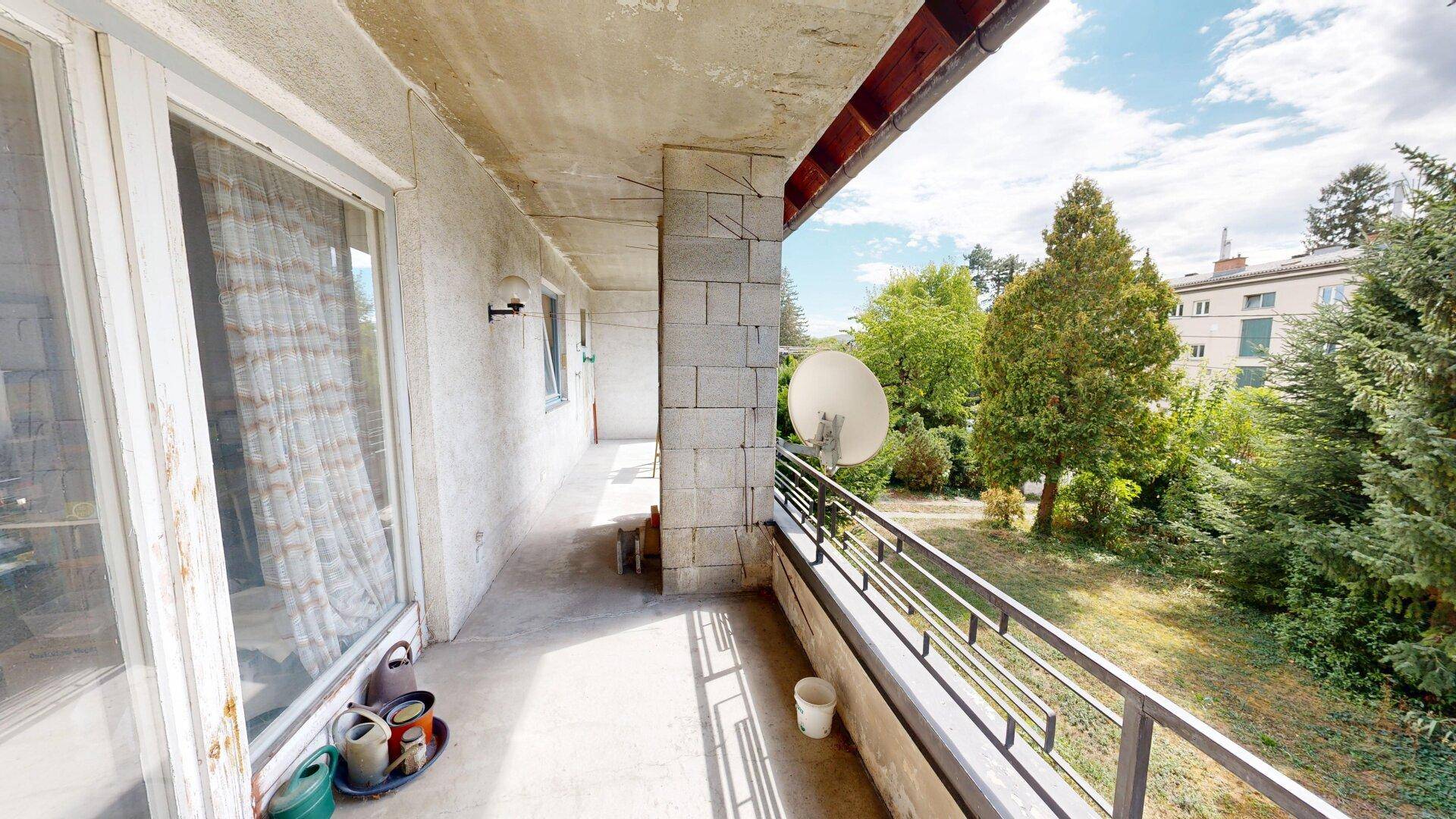 Langer Betonbalkon mit Satellitenschüssel und Blick ins Grüne, bietet Platz im Freien und Weitsicht.