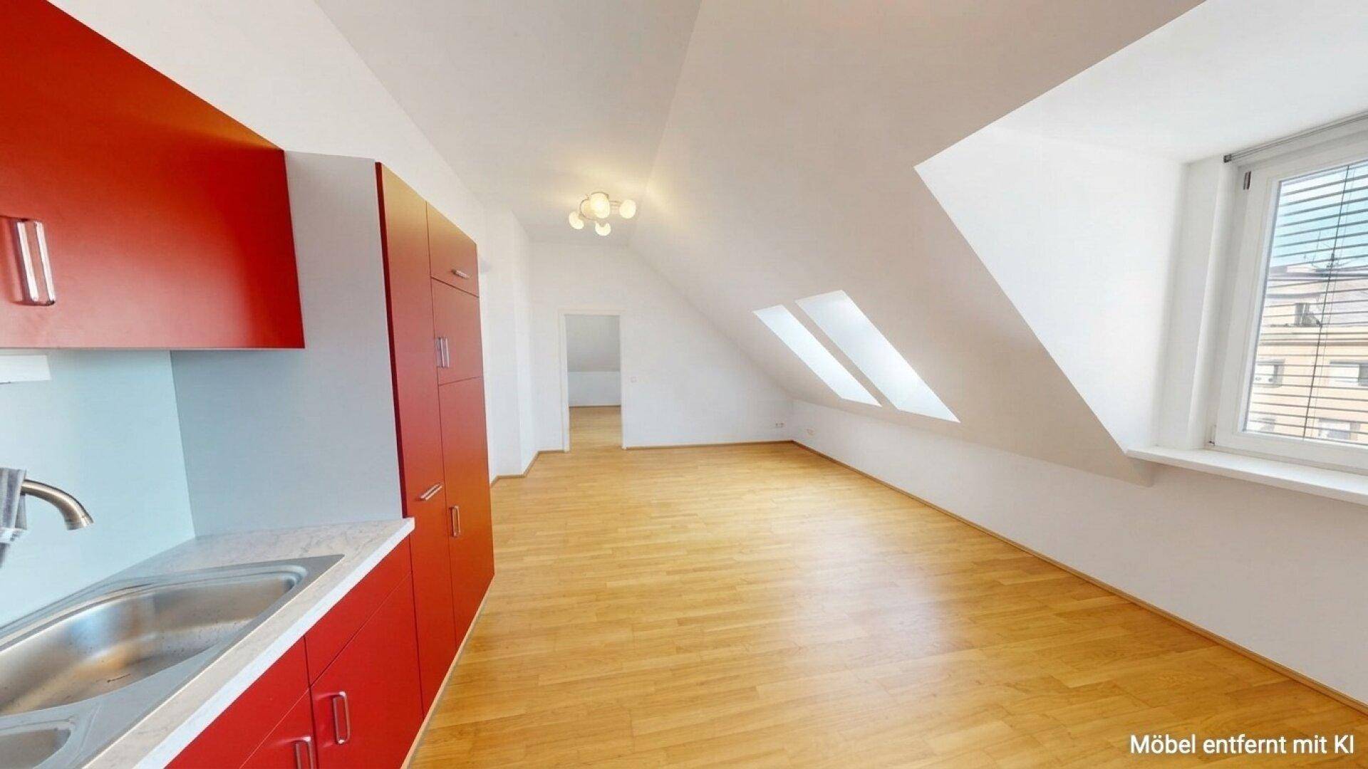 Offener Wohnbereich mit roter Einbauküche, Dachfenstern und hellem Holzparkettboden.