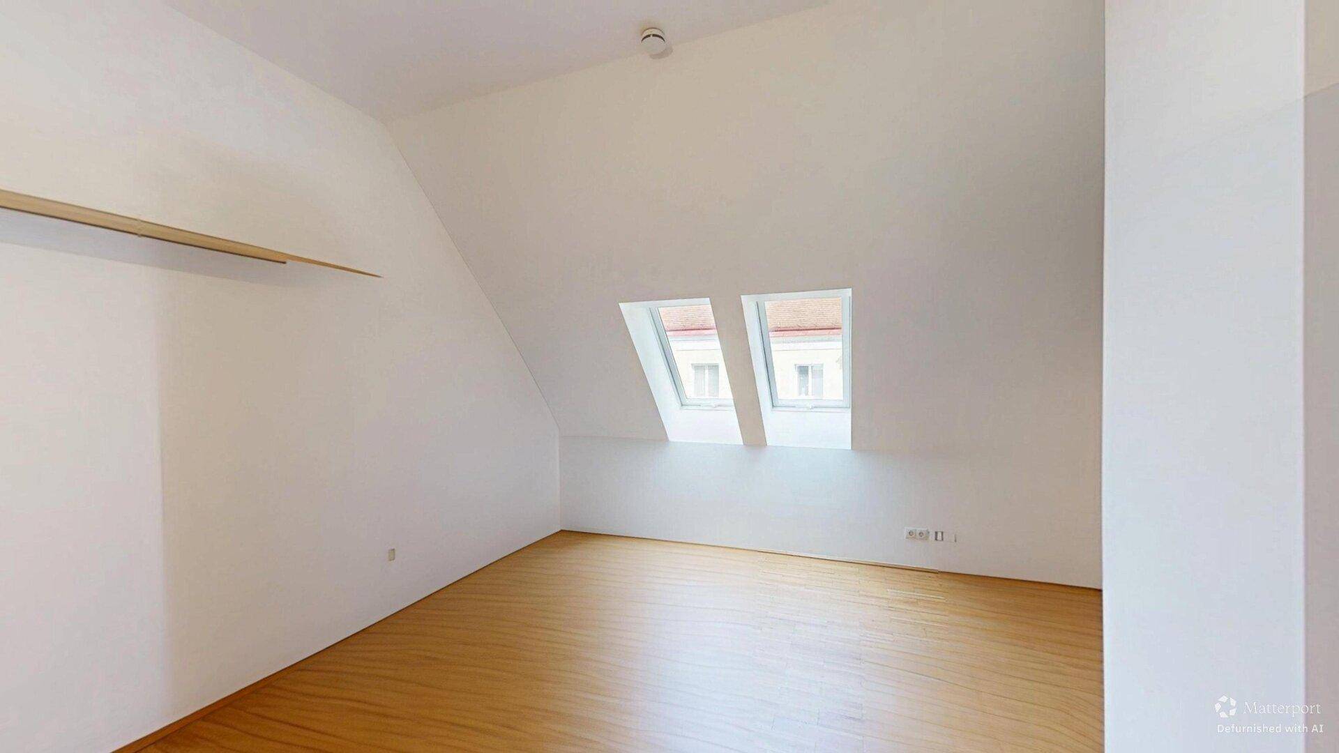 Lichtdurchflutetes Schlafzimmer im Dachgeschoss mit Parkettboden und schrägen Wänden.