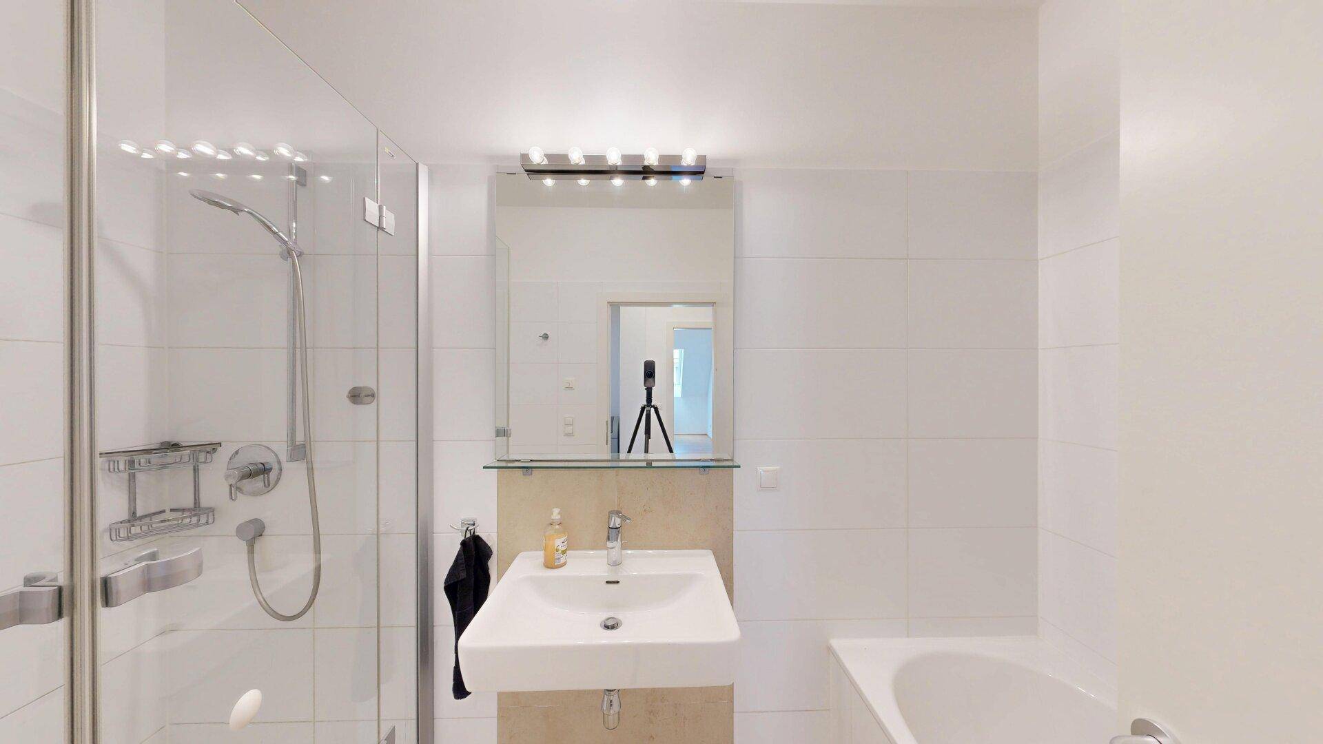 Helles Badezimmer mit Duschkabine, Badewanne und modernem Waschbecken.