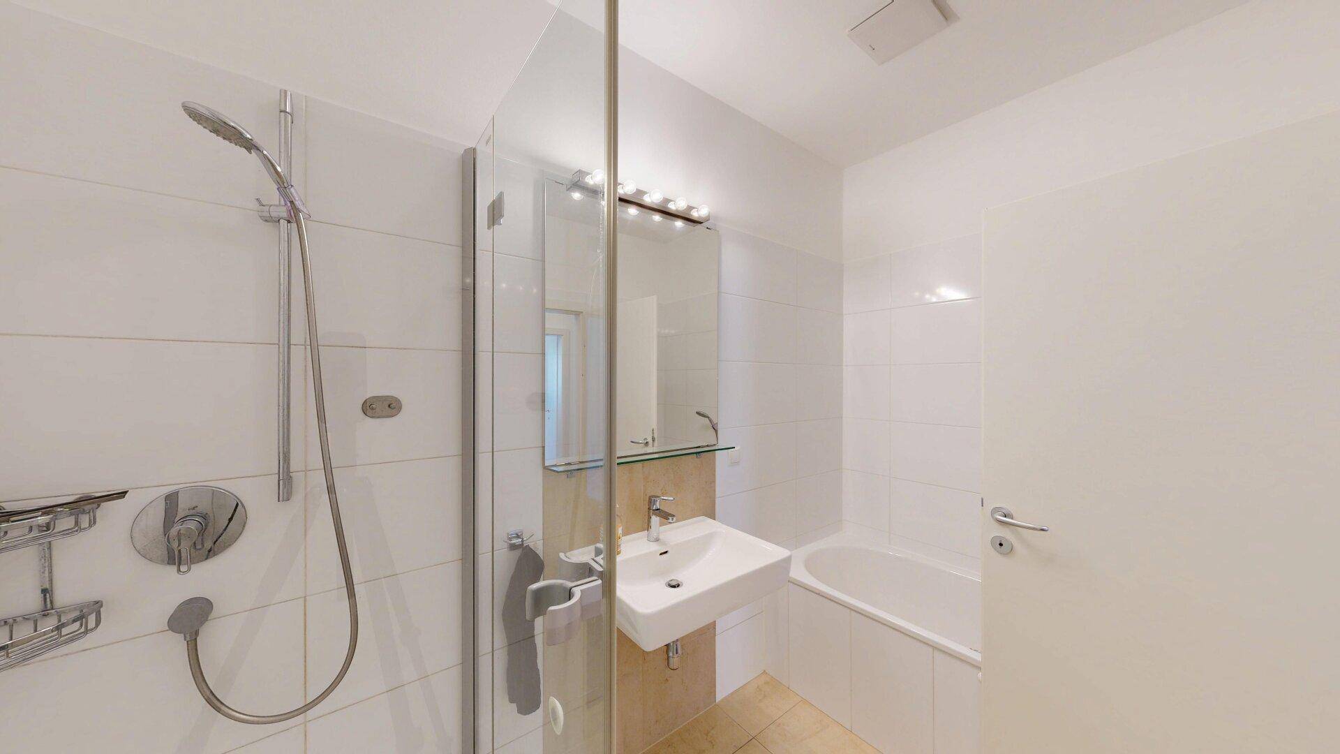 Funktionales Badezimmer mit Dusche, Badewanne und Waschtisch in neutralen Farben.